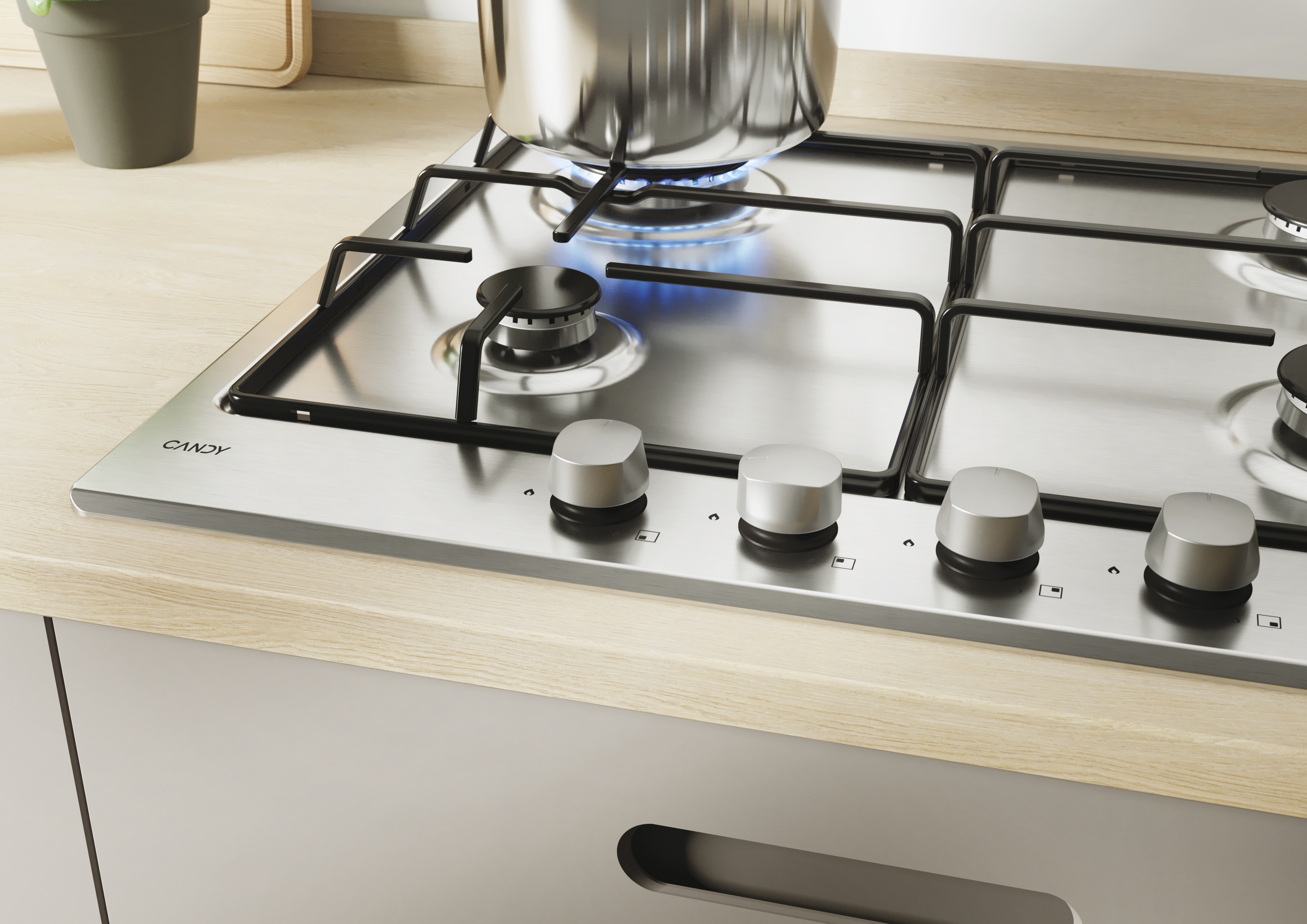 Zbliżenie na gazową płytę grzewczą z garnkiem, pokrętłami i blatem.