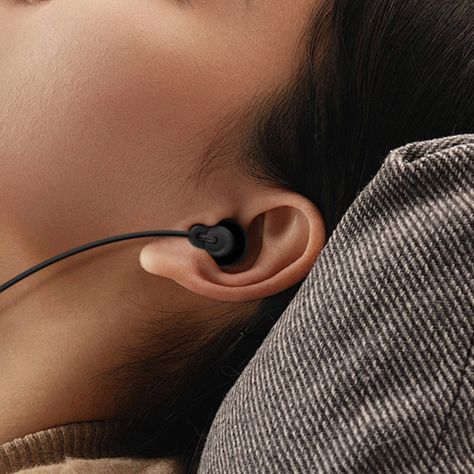 Una persona che indossa auricolari neri. Primo piano dell'orecchio e dell'auricolare.