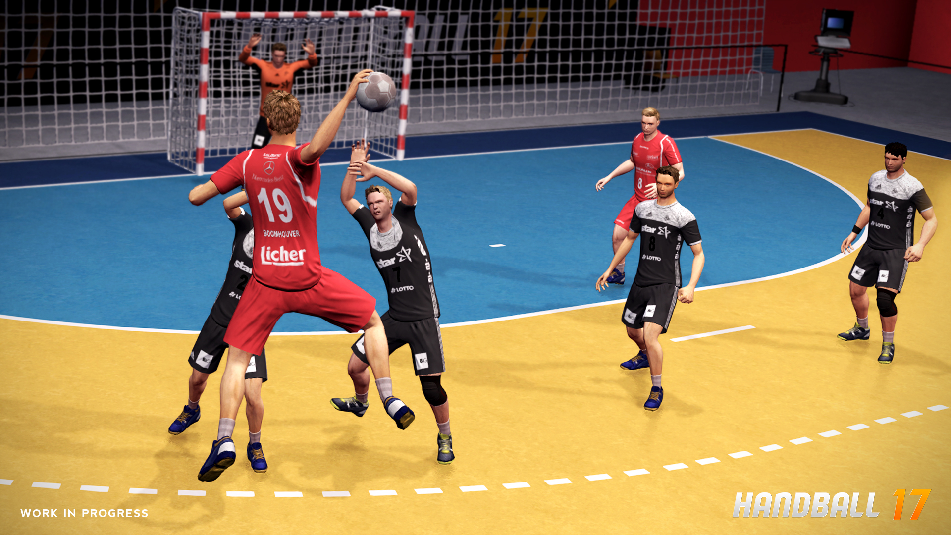 Handballspiel im Gange. Spieler in roten und schwarzen Uniformen, Ball in der Luft. Gelbes Feld, weißes Netz.
