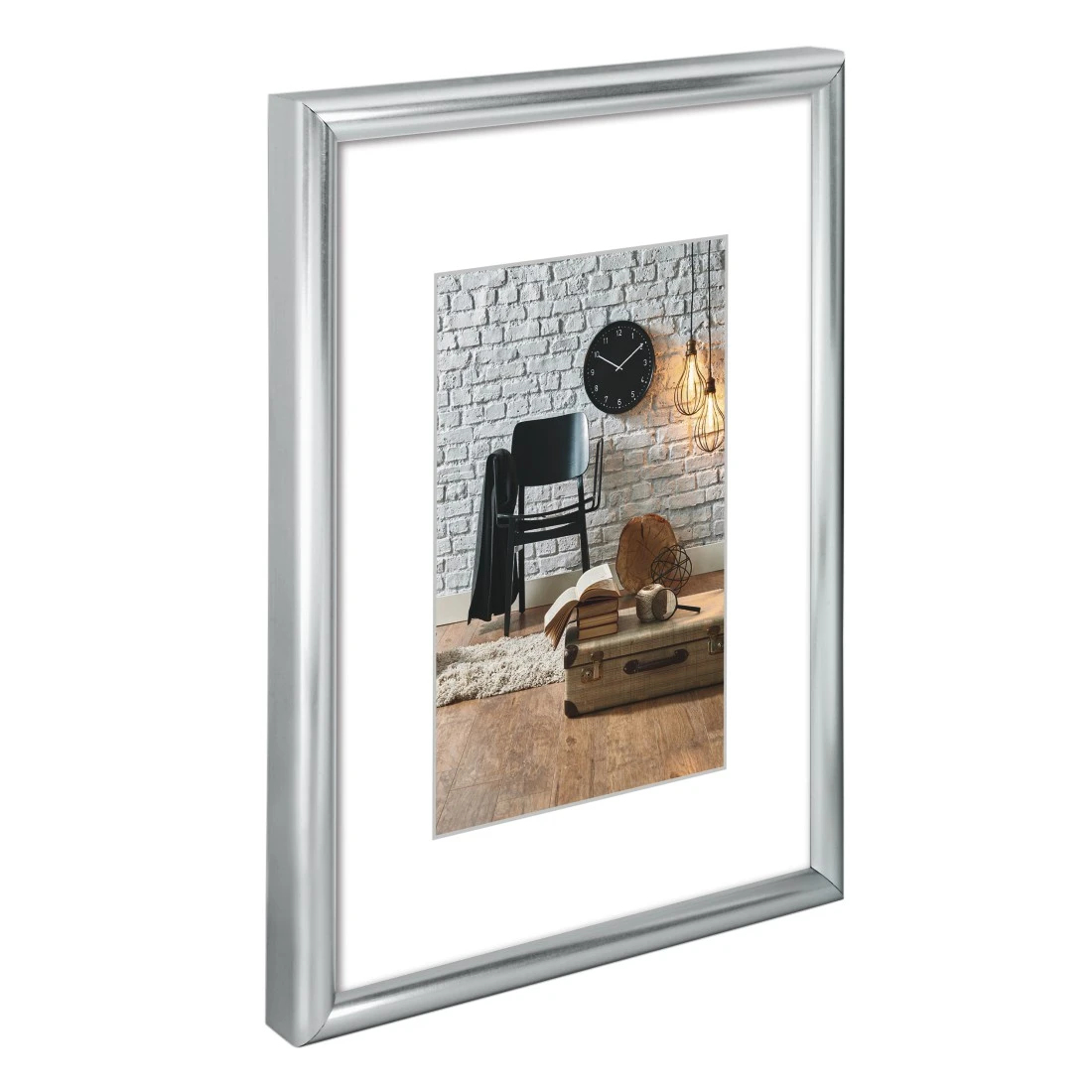 Srebrna rama ze zdjęciem czarnego krzesła, zegara i książek na białej ceglanej ścianie.