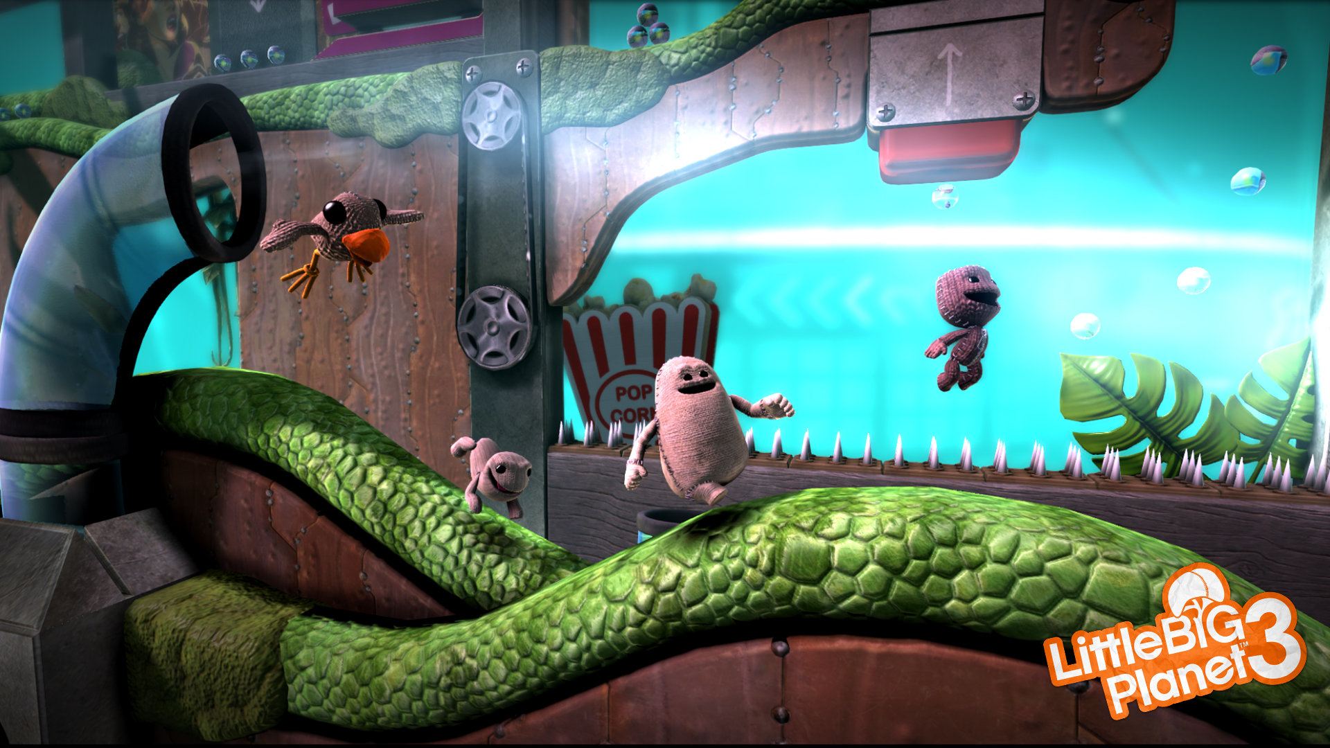 Personajes de LittleBigPlanet en una plataforma con una superficie verde ondulada. Hay una caja de palomitas y un ventilador.