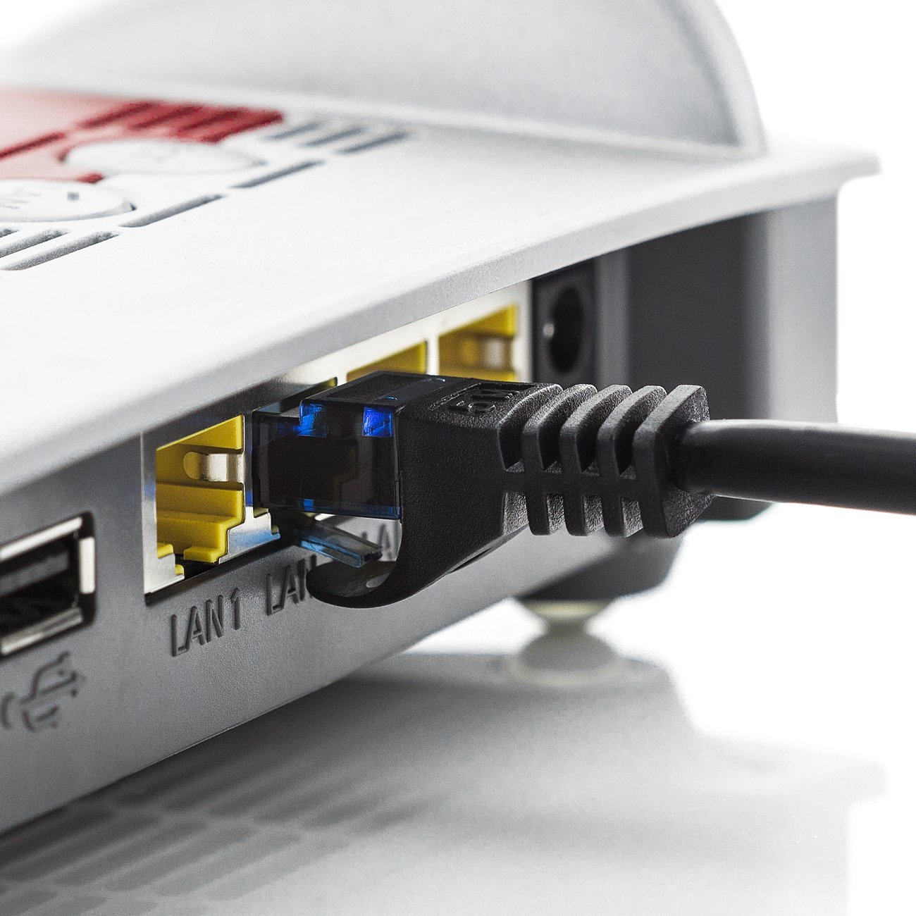 Netzwerkkabel in einen Router gesteckt. Das Kabel hat einen blauen Stecker. Der Router ist grau.