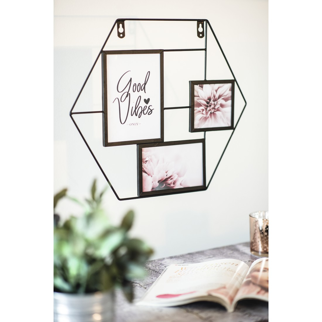 Une décoration murale avec des photos et un magazine sur une table avec une plante.