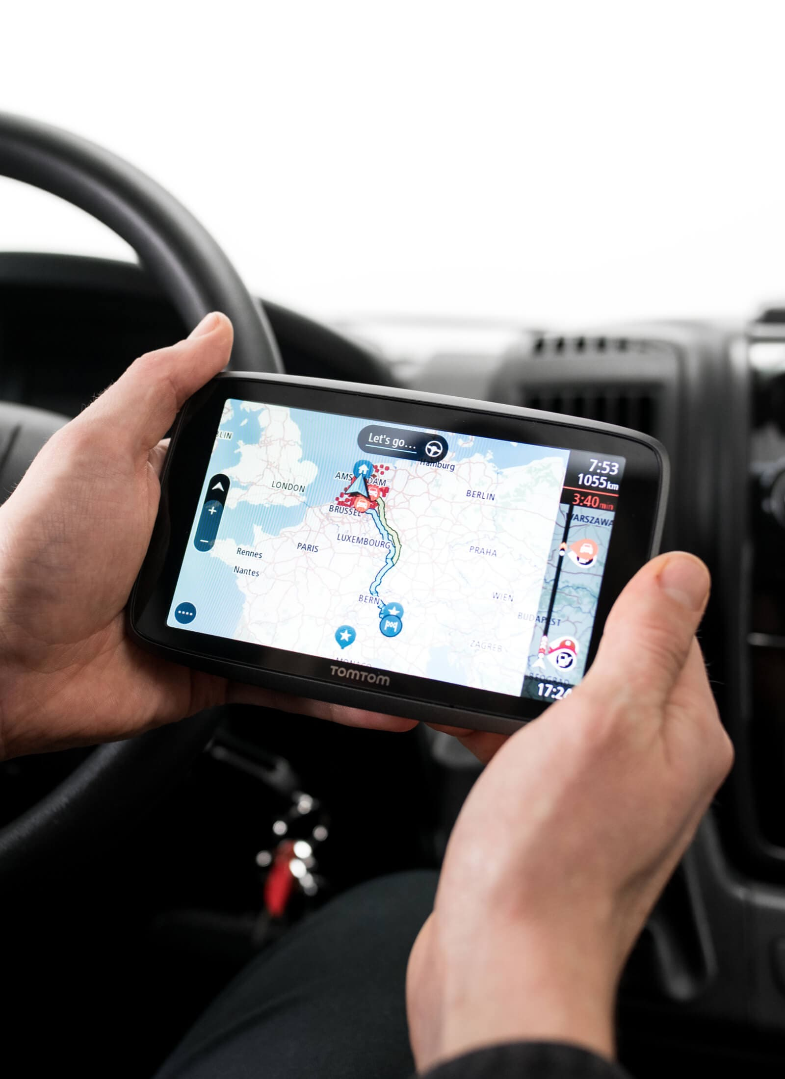 Hände halten ein TomTom-GPS in einem Auto. GPS zeigt eine Karte an.