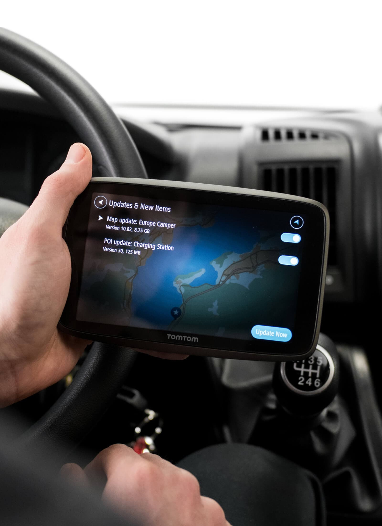 Hände, die ein TomTom-GPS in einem Auto halten. Kartenaktualisierungsbildschirm.
