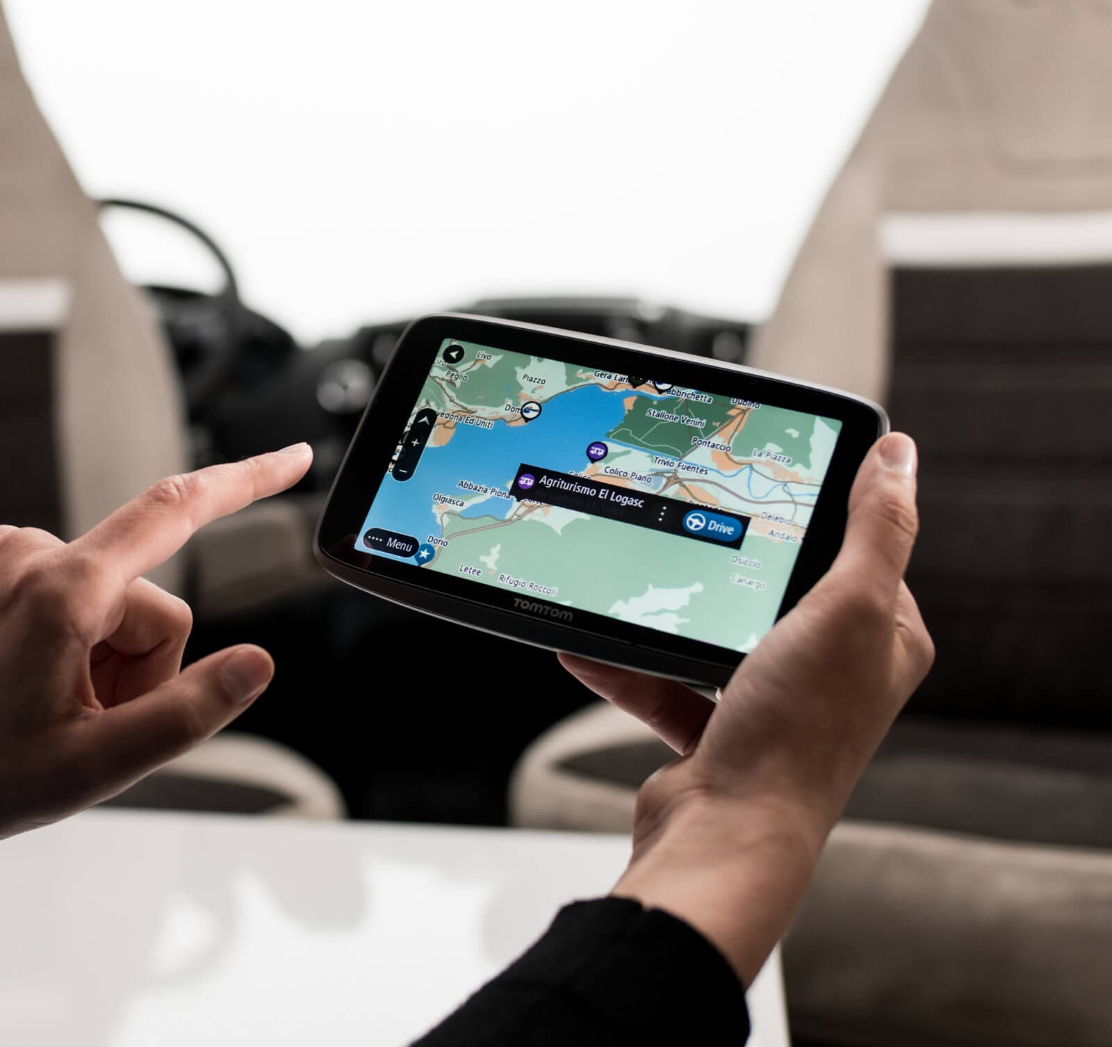 Hände halten TomTom-GPS. GPS zeigt Karte und Menüoptionen an.