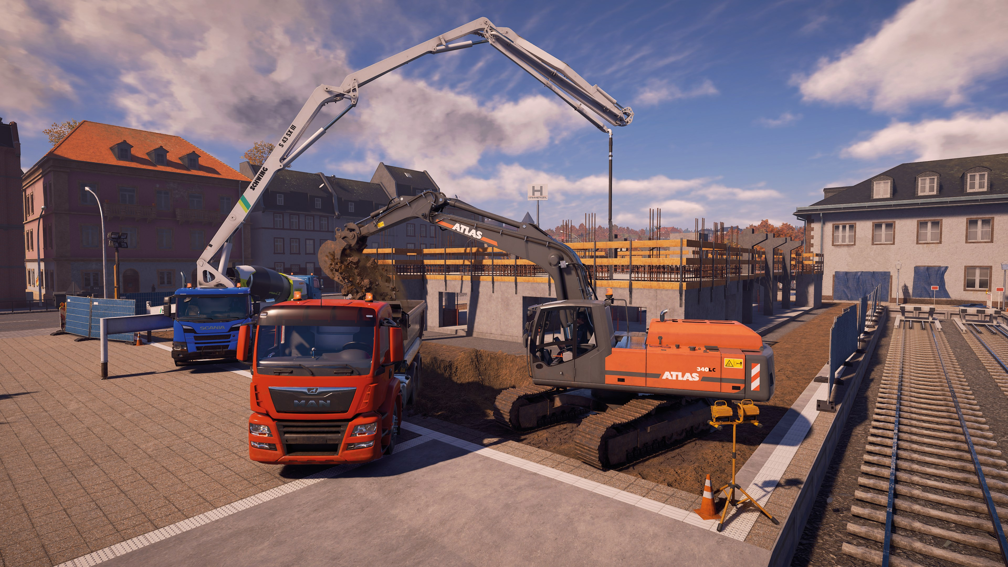 Baustelle mit MAN-LKW, Atlas-Bagger, Betonpumpe und im Bau befindlichen Gebäuden.