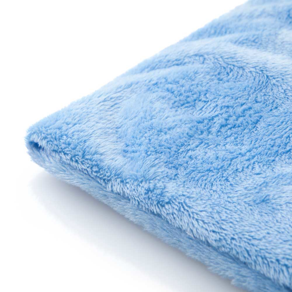 Zbliżenie niebieskiego, puszystego koca na białym tle.