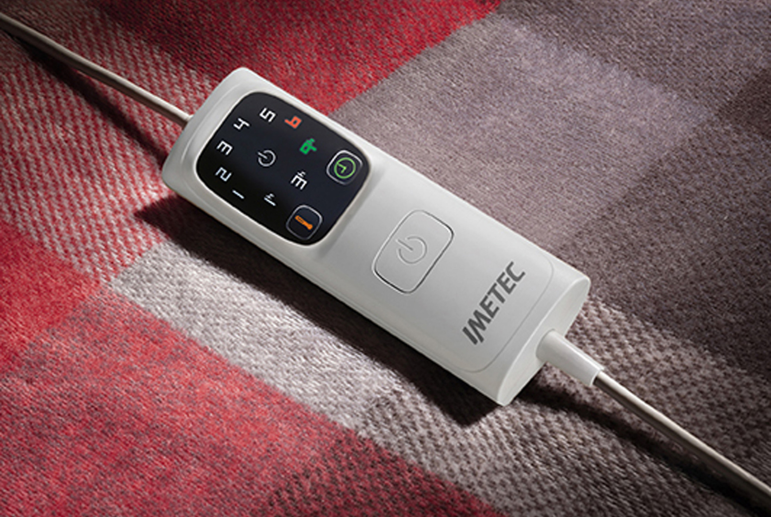 Controller bianco con pulsanti e schermo su coperta rossa e grigia. Primo piano.