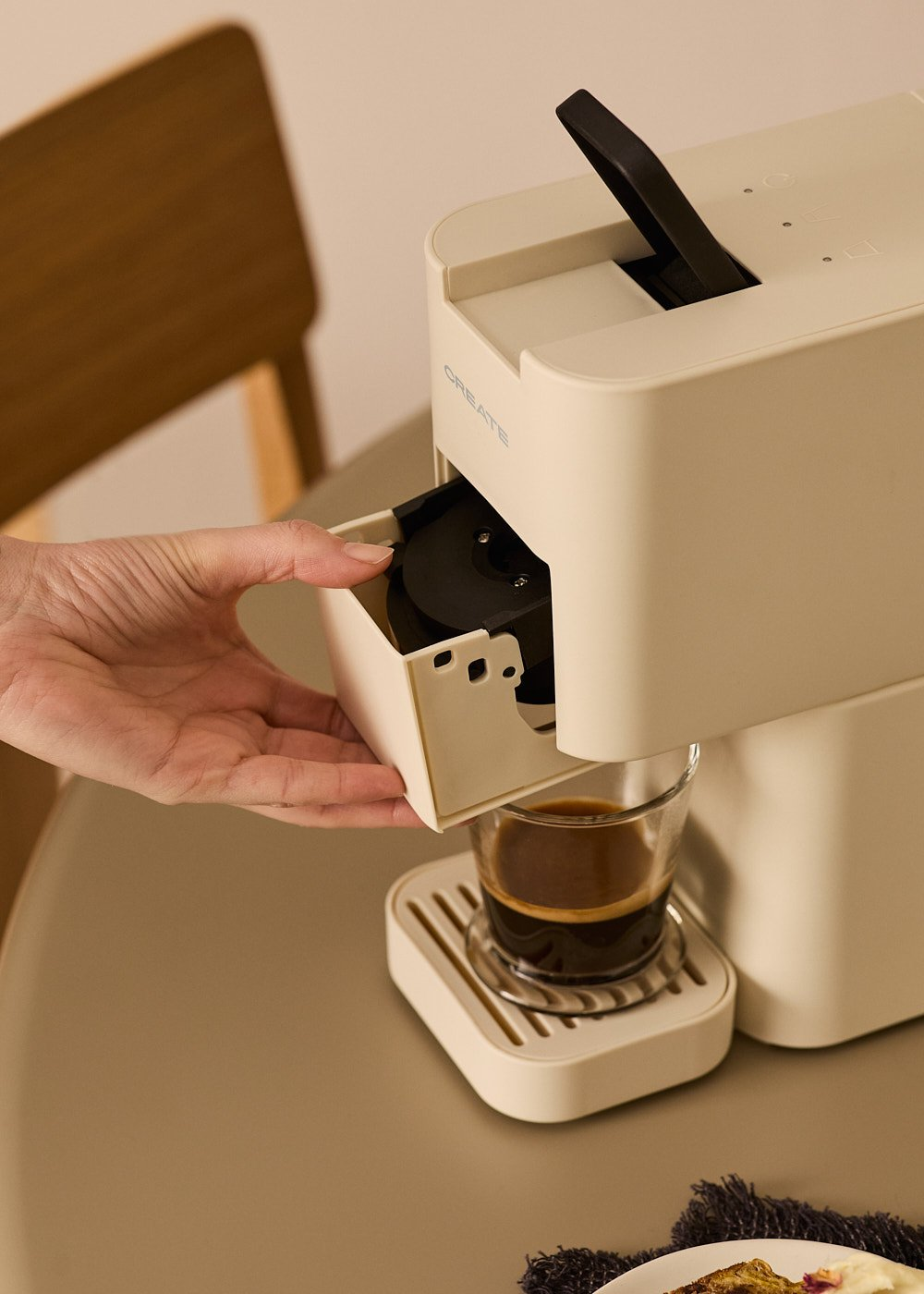 Una persona usando una cafetera CREATE blanca, preparando café en un vaso.