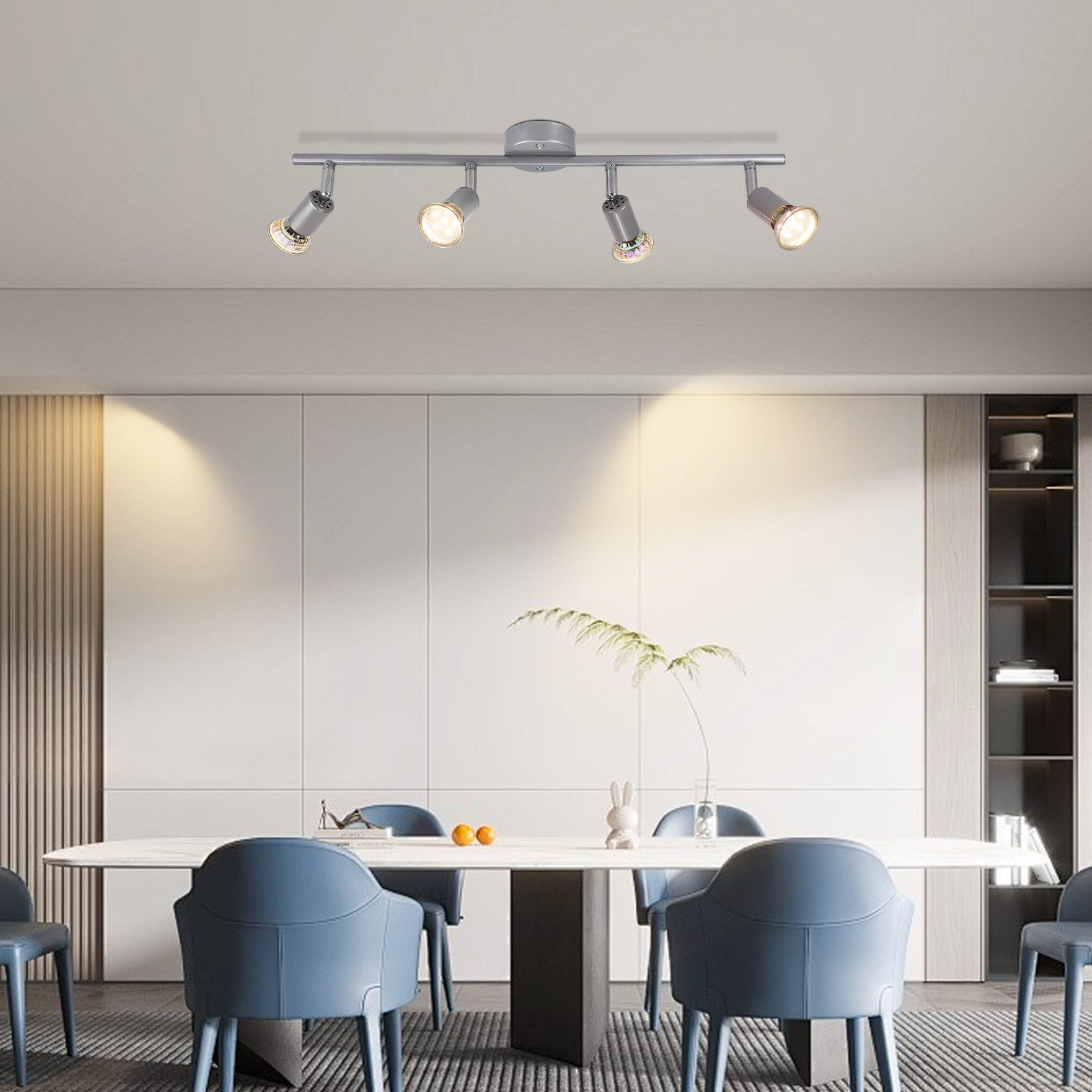Jadalnia z długim stołem, niebieskimi krzesłami i lampą sufitową z reflektorami.