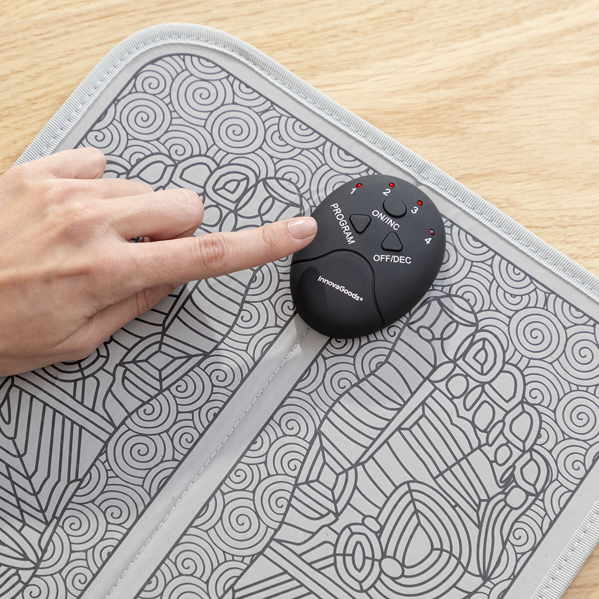 Palec naciska przycisk 'PROGRAM' na panelu sterowania masażera do stóp InnovaGoods.