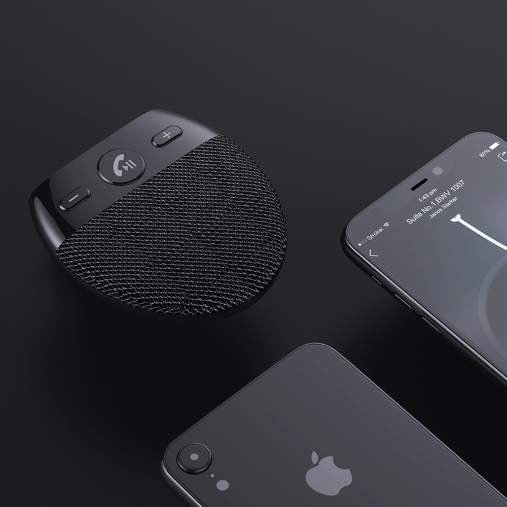Schwarzer Bluetooth-Autolautsprecher mit Telefon und einem anderen Telefon auf dunkler Oberfläche.
