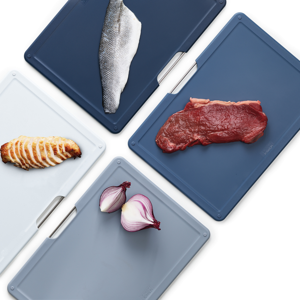 Schneidebretter mit verschiedenen Lebensmitteln: Fischfilet, Steak, Hähnchen und rote Zwiebel. Alles auf weißem Hintergrund.