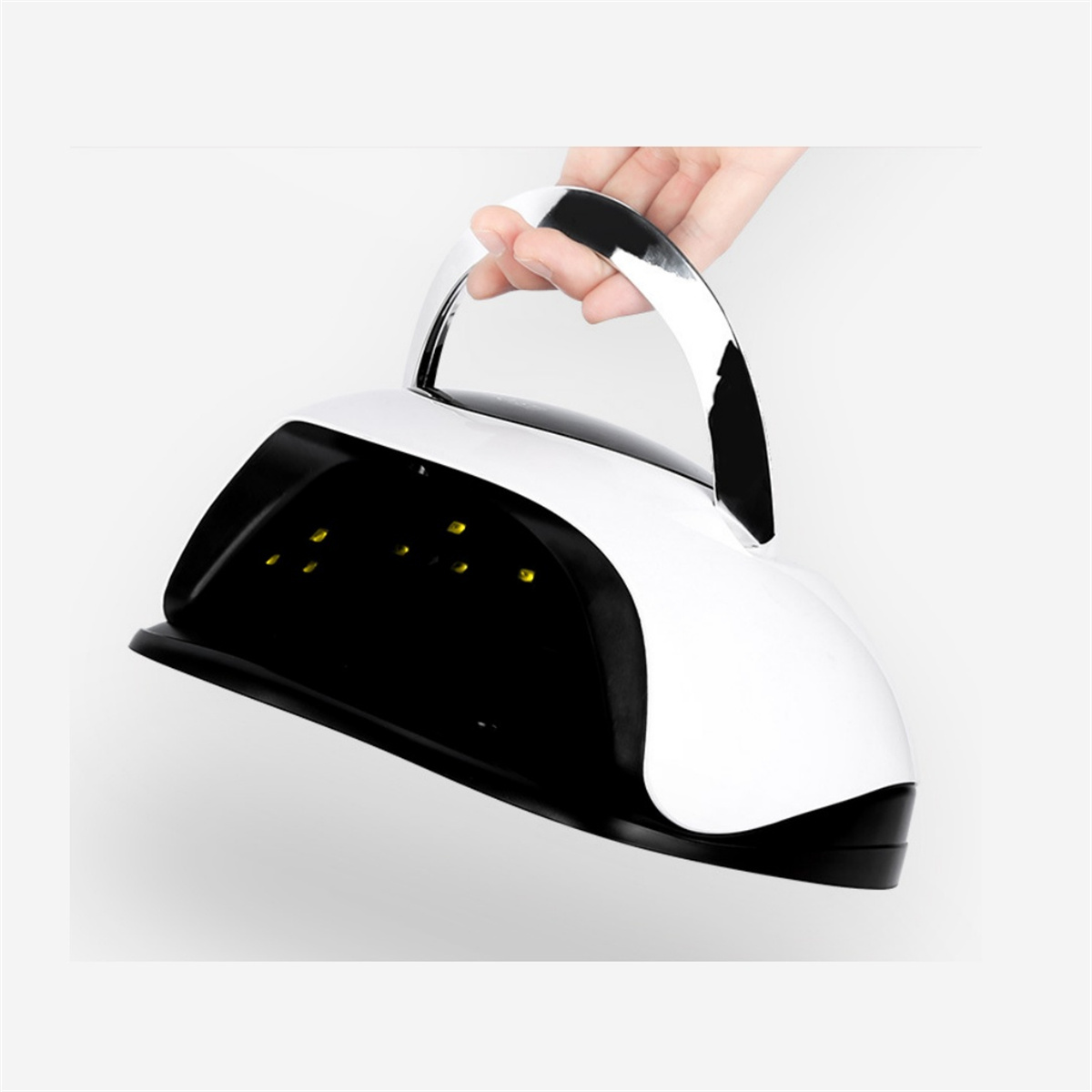 Eine Hand hält eine Nagellampe, weiß und schwarz, über einem weißen Hintergrund. Die Lampe ist nach oben geneigt.