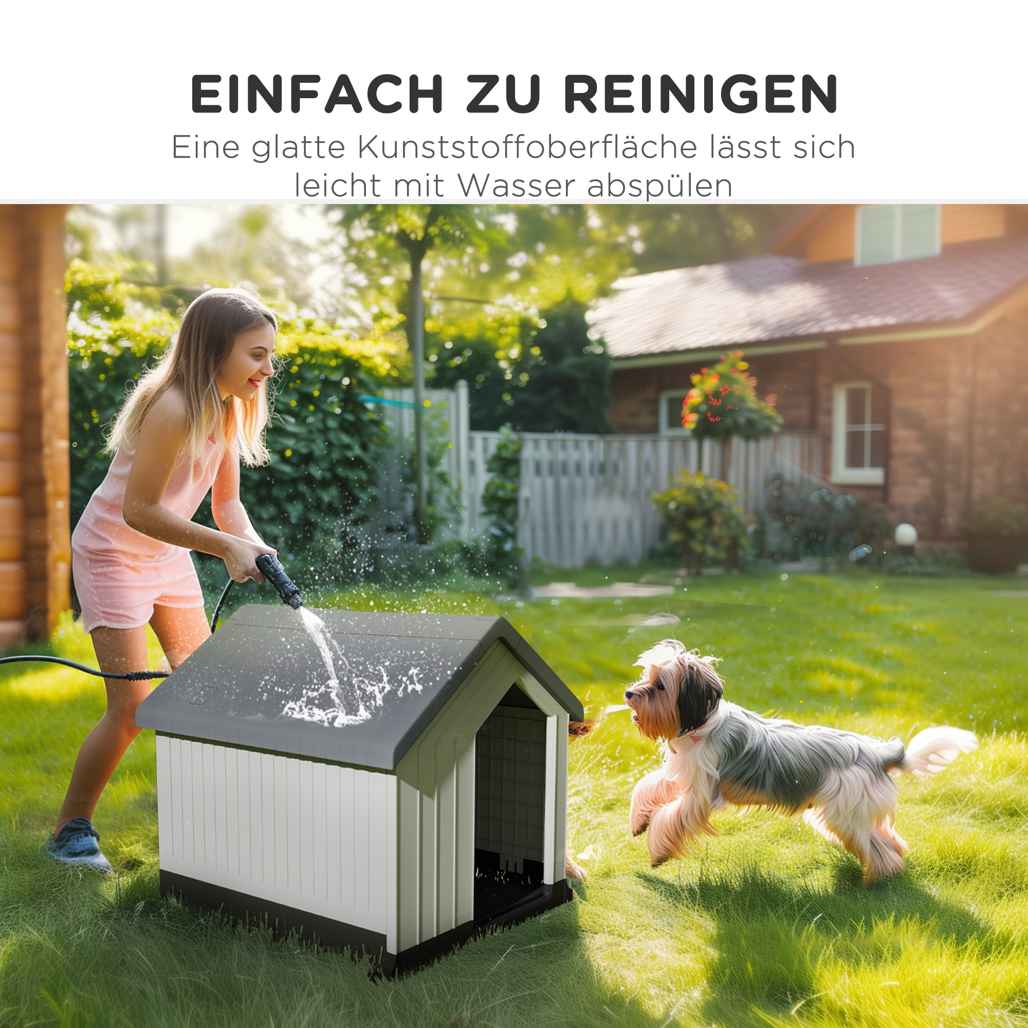 Mädchen sprüht Wasser auf ein Hundehaus. Hund springt weg. Grünes Gras, Haus und Bäume im Hintergrund.