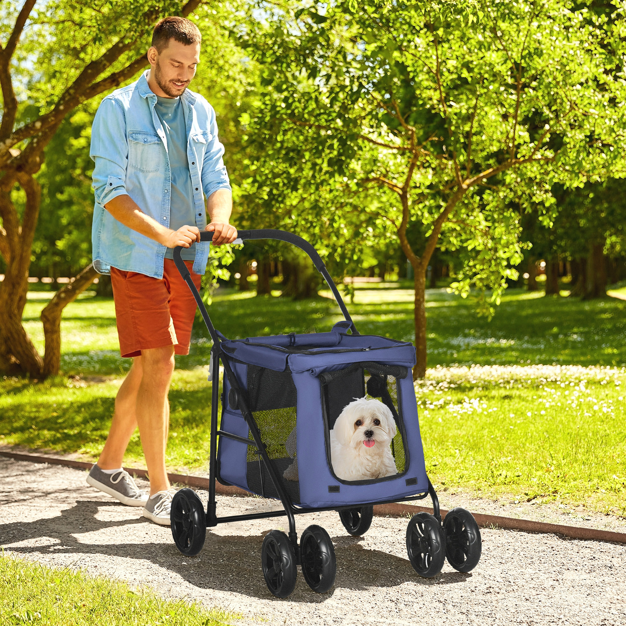 Mann, der einen Hund in einem blauen Tierkinderwagen durch einen Park führt.