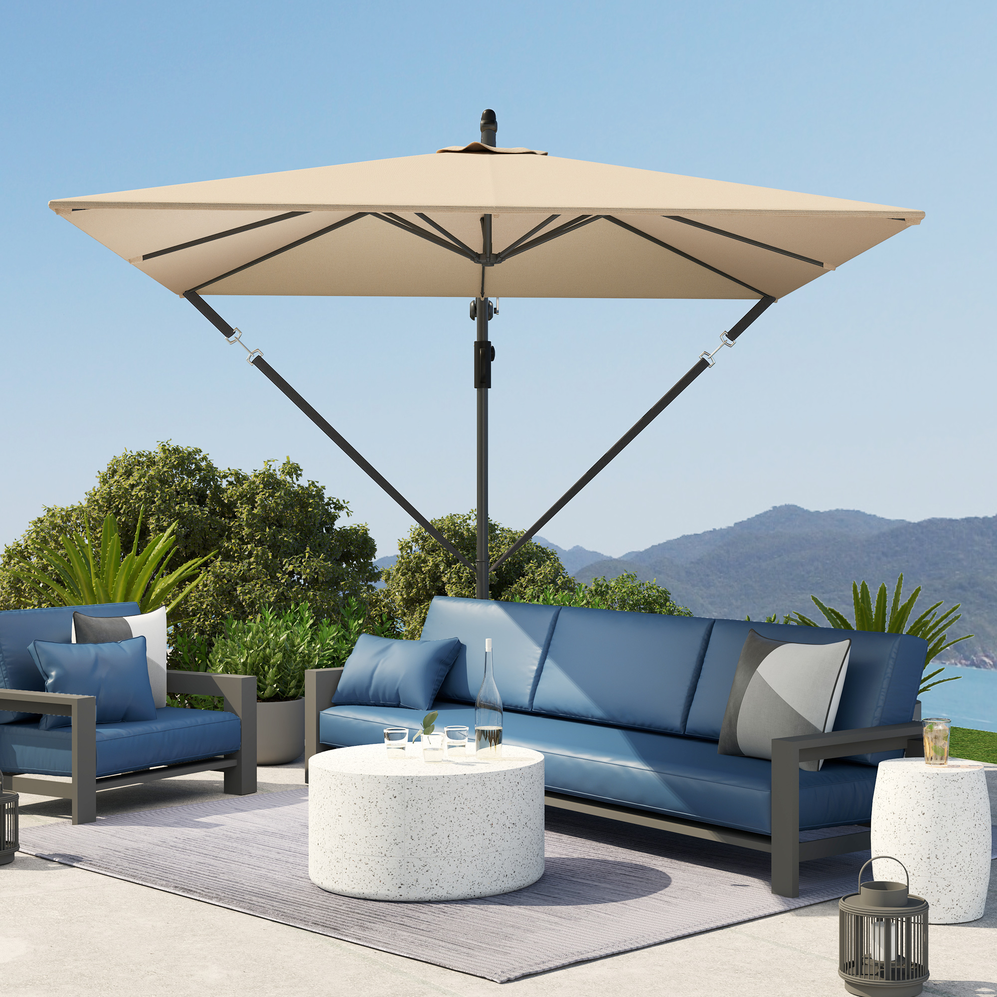 Una scena di patio con un divano blu, una sedia e un ombrellone quadrato beige. Montagne sullo sfondo.