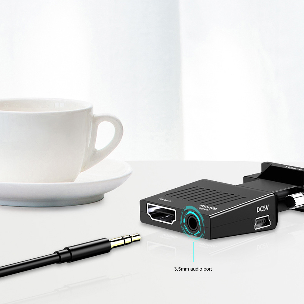 Eine weiße Tasse und Untertasse auf einem Tisch mit einem schwarzen Adapter und einer 3,5-mm-Audiobuchse. Der schwarze Adapter hat HDMI- und Audioanschlüsse.