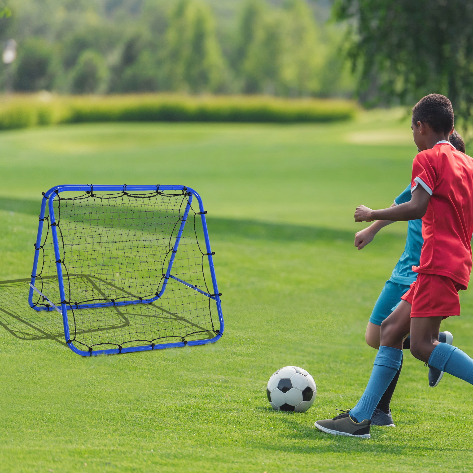 Zwei Jungen in roten und blauen Fußballtrikots spielen Fußball in der Nähe eines blauen Netzes.