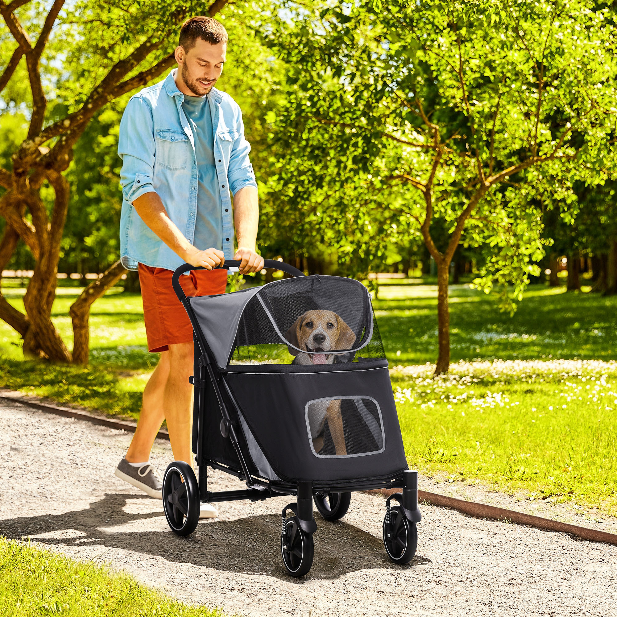 Ein Mann schiebt einen schwarz-grauen Tierbuggy mit einem Hund darin, der auf einem Weg geht.