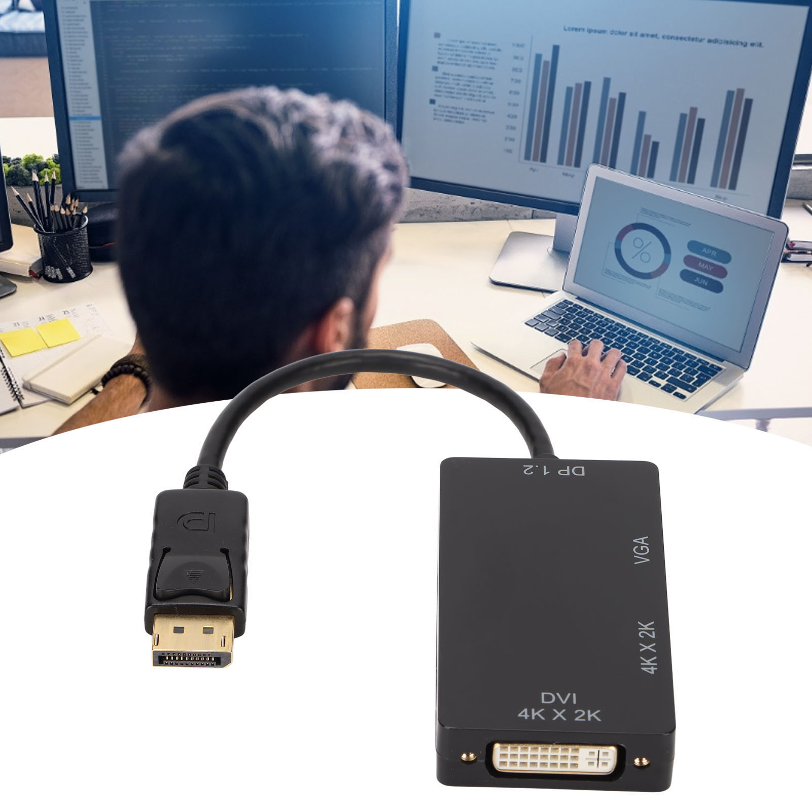 Ein schwarzer Adapter, der einen DP-Anschluss mit einem DVI- und VGA-Anschluss verbindet. Zwei Monitore und ein Laptop im Hintergrund.