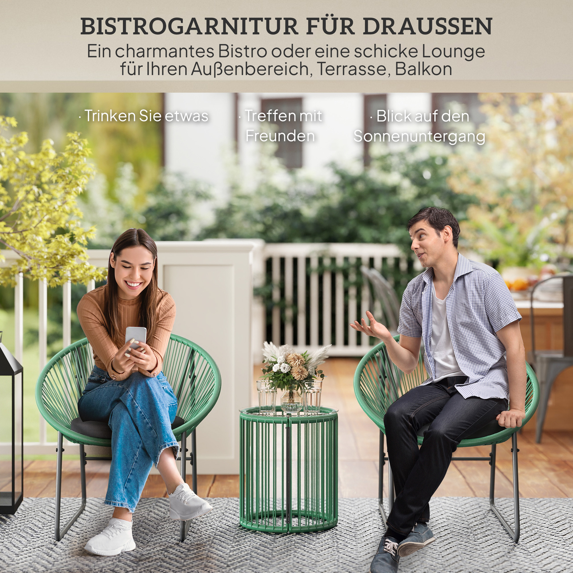 Ein Mann und eine Frau auf einer Terrasse, sitzen in grünen Stühlen, interagieren mit einem Tisch.