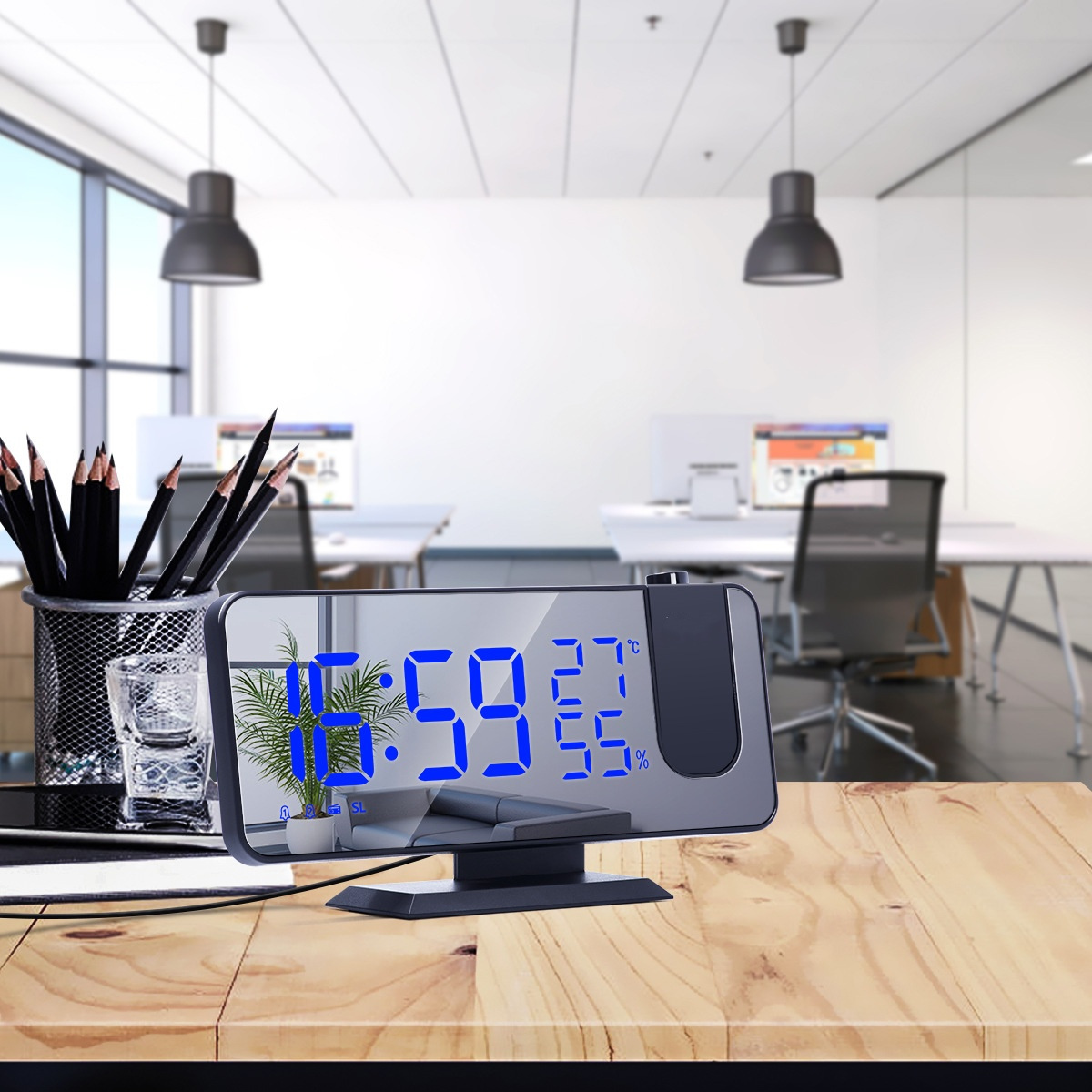 Eine Digitaluhr zeigt 16:59 Uhr an. Im Hintergrund sind Bürotische und Lichter zu sehen.