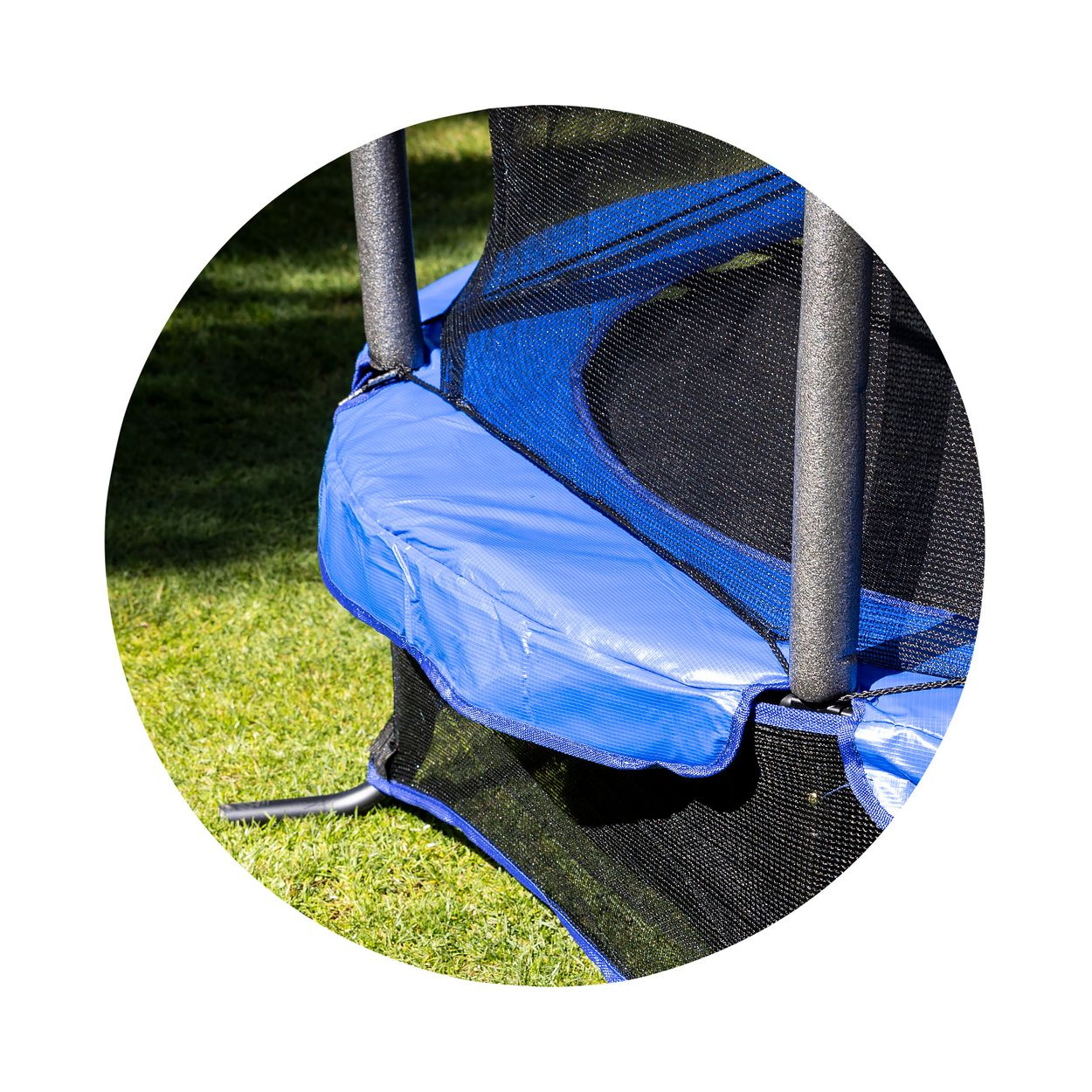 Trampolin mit blauem Rahmen und blauer Polsterung. Grünes Gras im Hintergrund. Kreisförmiger Rahmen.