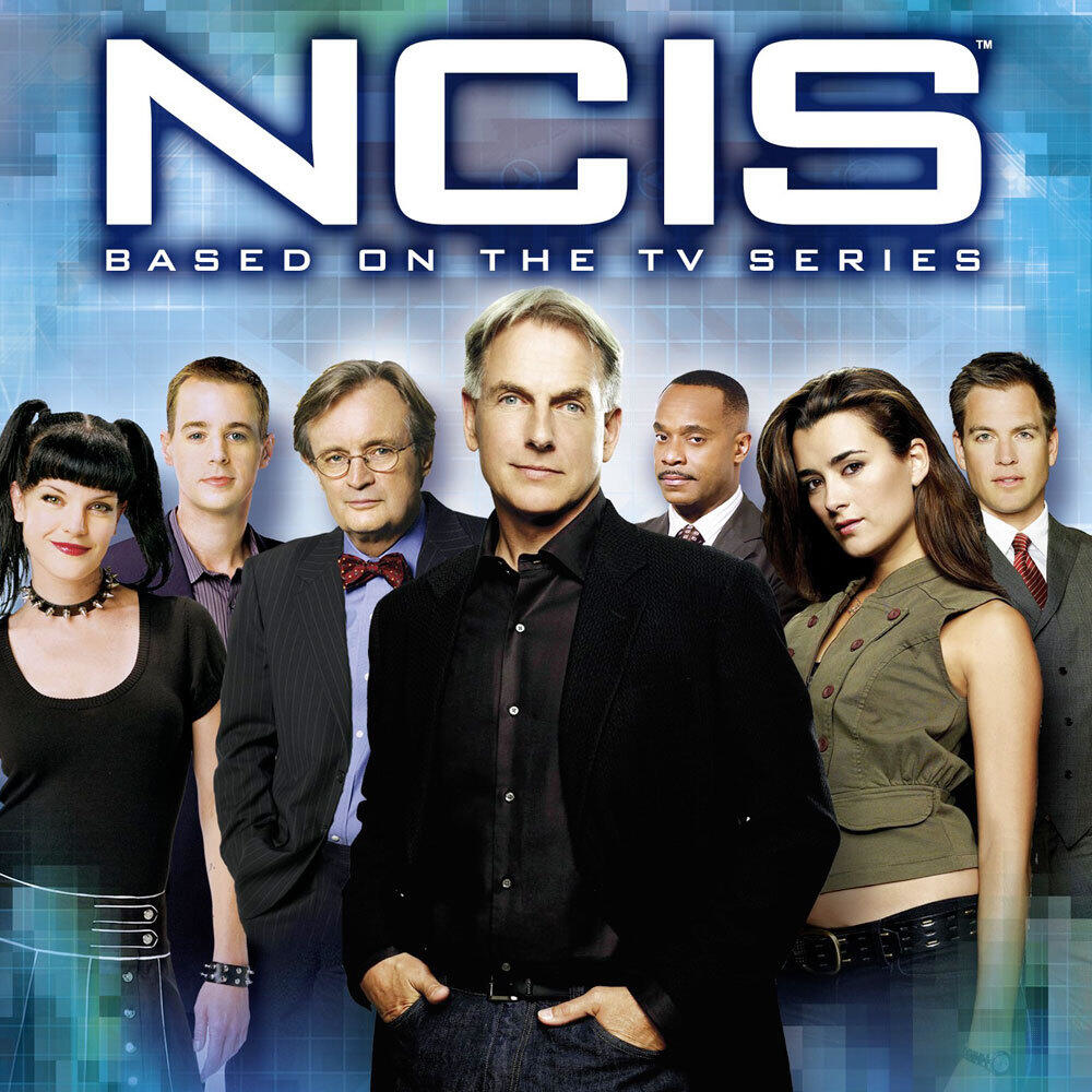 NCIS-Cast-Foto. Sieben Personen, meist in Geschäftskleidung, vor blauem Hintergrund.