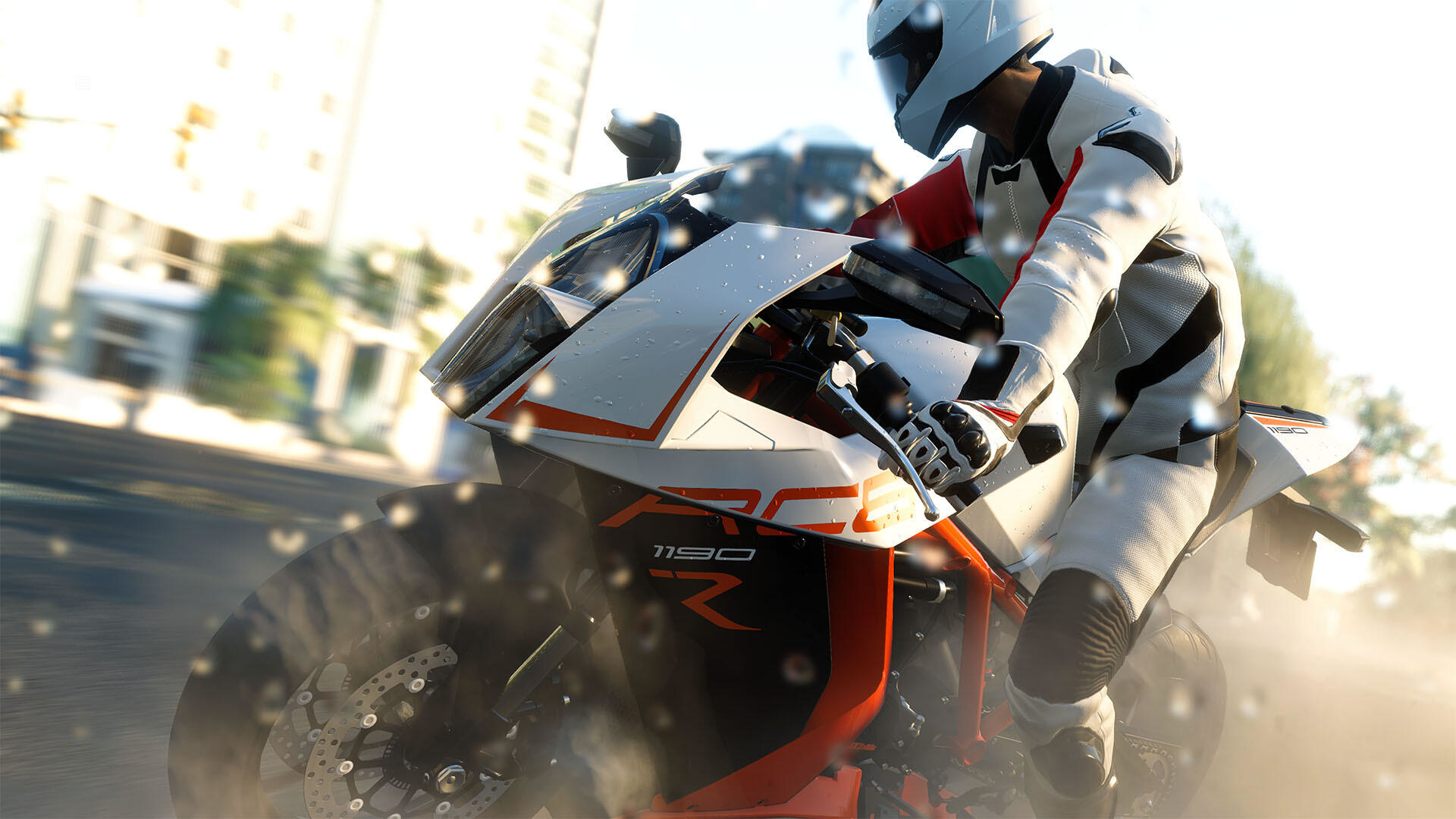 Osoba na motocyklu pochyla się w zakręcie. Motocykl jest biało-pomarańczowy, droga jest mokra.