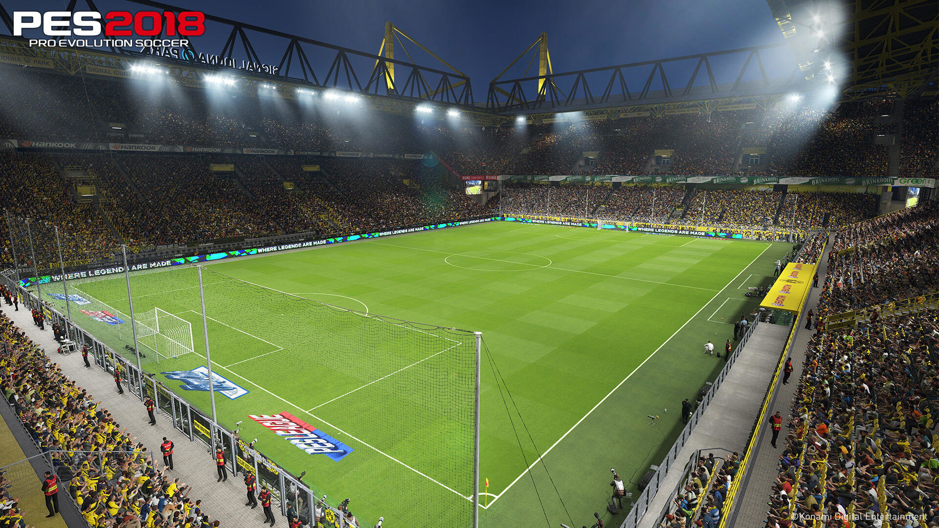 Stadion piłkarski. Zielone boisko otoczone żółtymi siedzeniami.