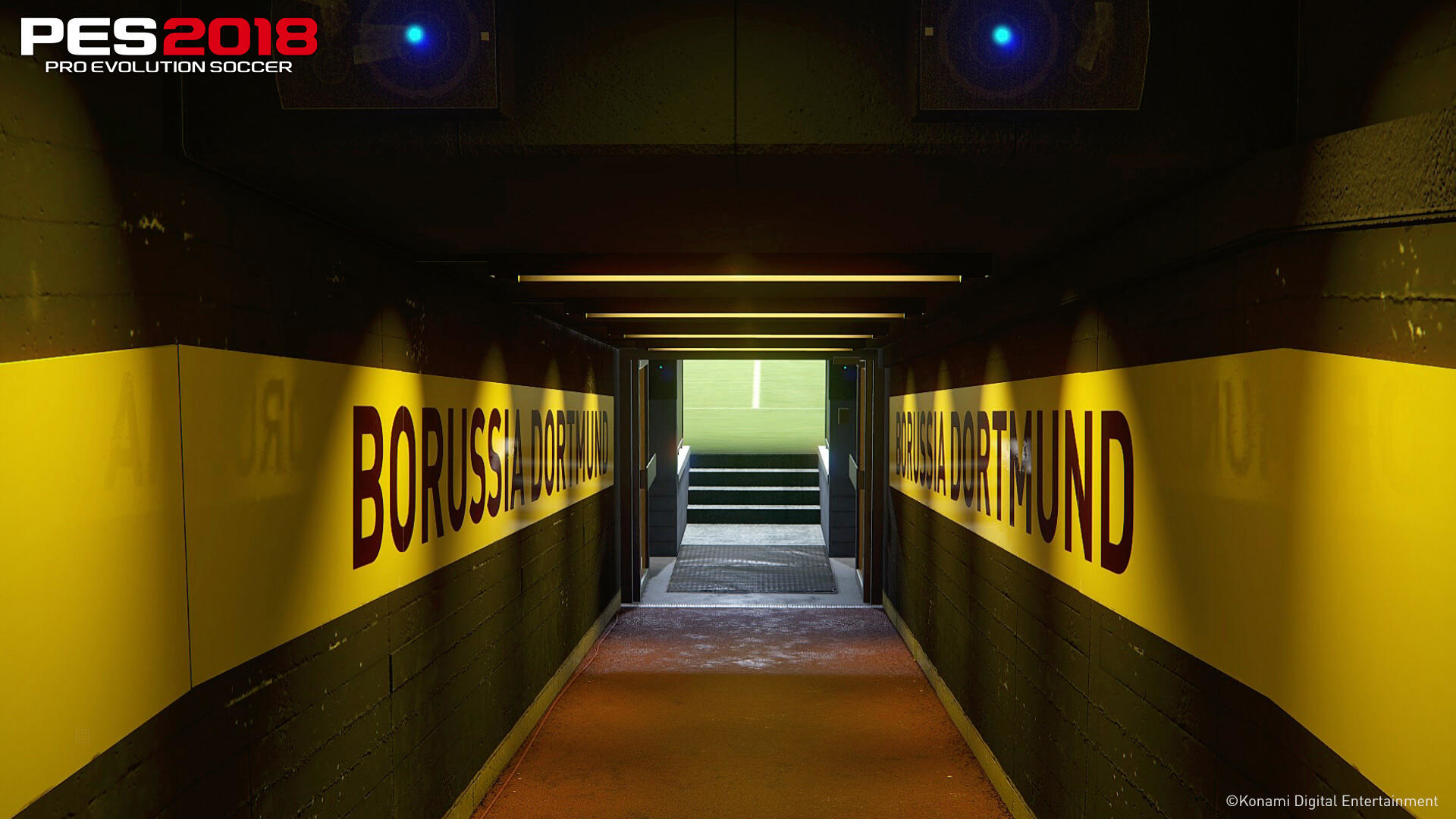 Tunel z napisem 'BORUSSIA DORTMUND' na ścianach. Boisko stadionu widoczne na końcu.