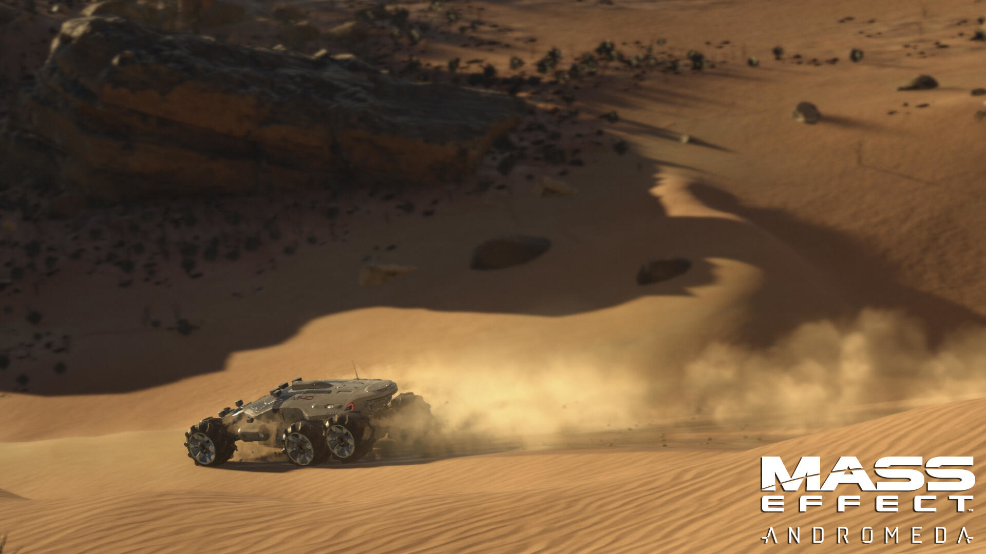 Un veicolo solleva polvere su un pianeta deserto. Il logo Mass Effect: Andromeda è in basso a destra.