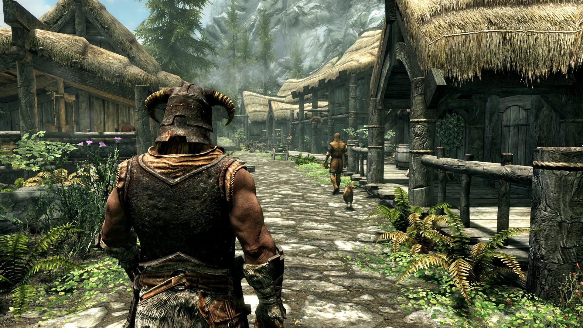 Scena z gry Skyrim: mężczyzna w zbroi przechodzi przez wioskę z budynkami o strzechowych dachach.