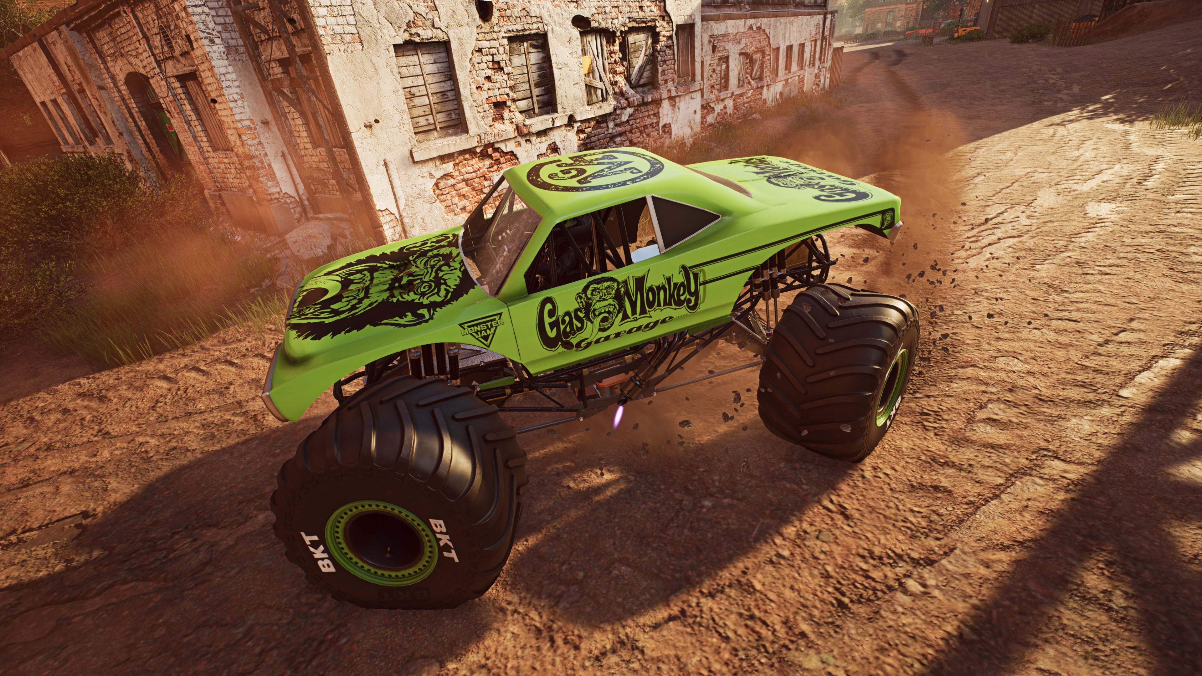 Zielony monster truck Gas Monkey Garage jedzie po polnej drodze, podnosząc kurz.