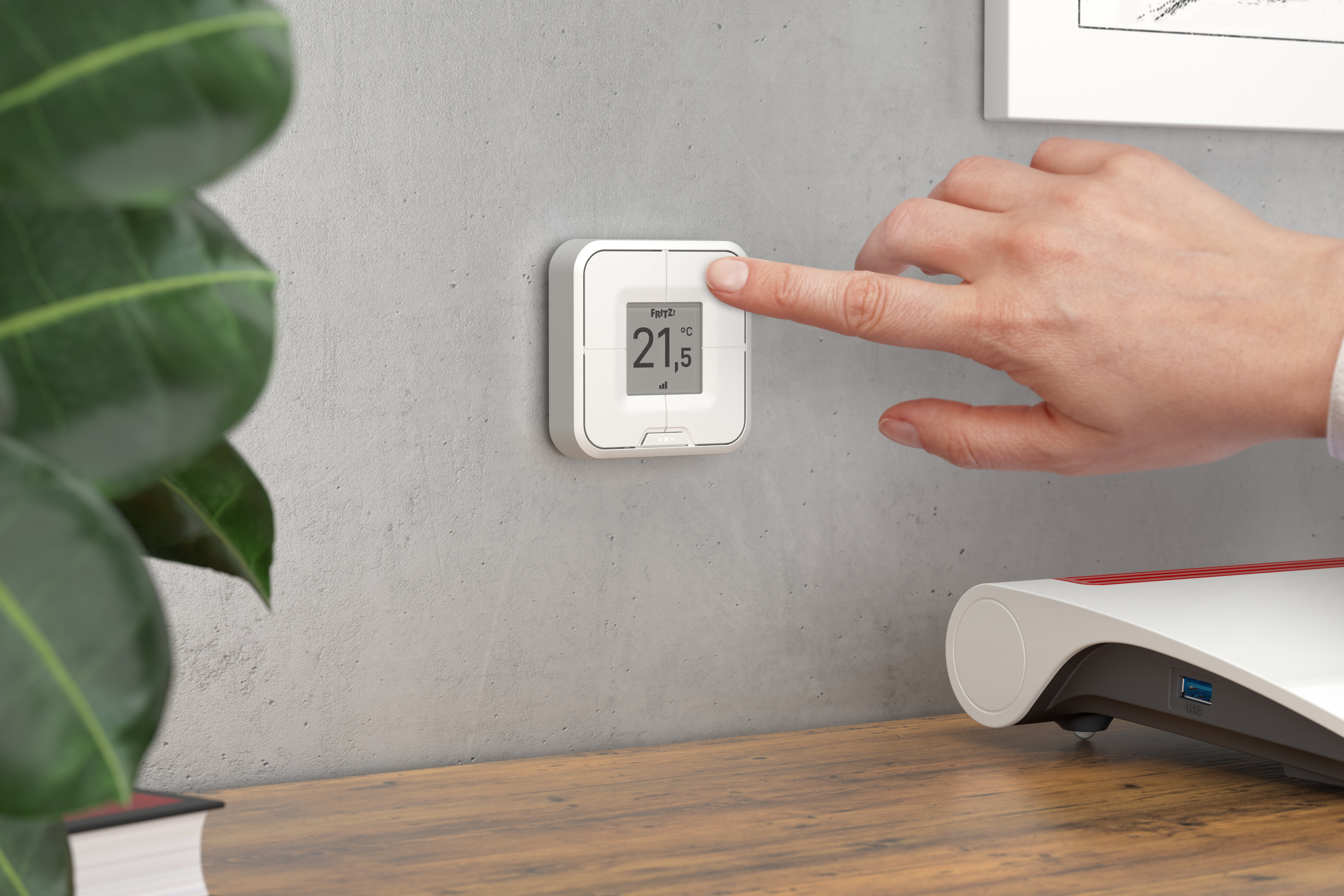 Hand berührt ein weißes digitales Thermostat, das 21,5 Grad an einer grauen Wand anzeigt.