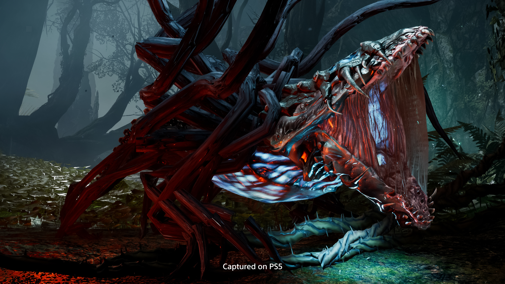 Potwór z ostrymi zębami i pnączami, w ciemnym lesie. U dołu napis "Captured on PS5".