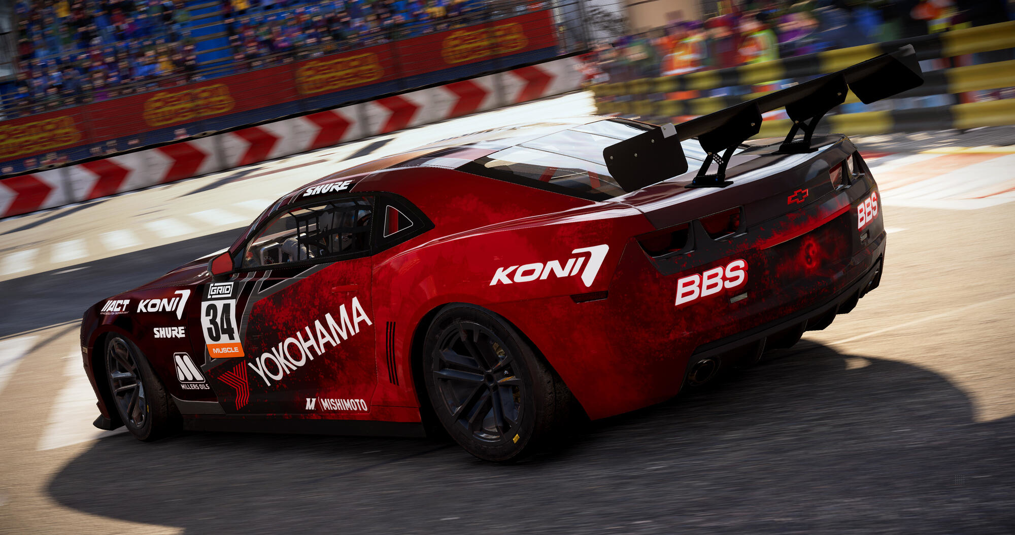 Czerwony samochód wyścigowy z logo sponsorów, na torze wyścigowym, widok z boku.