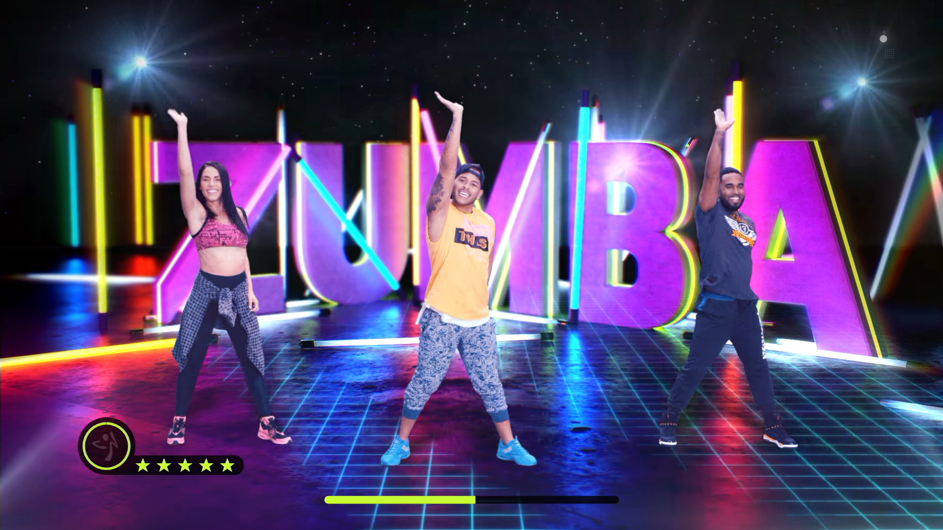 Drei Personen tanzen auf einer Bühne mit dem Wort ZUMBA im Hintergrund. Lichter sind im Hintergrund.