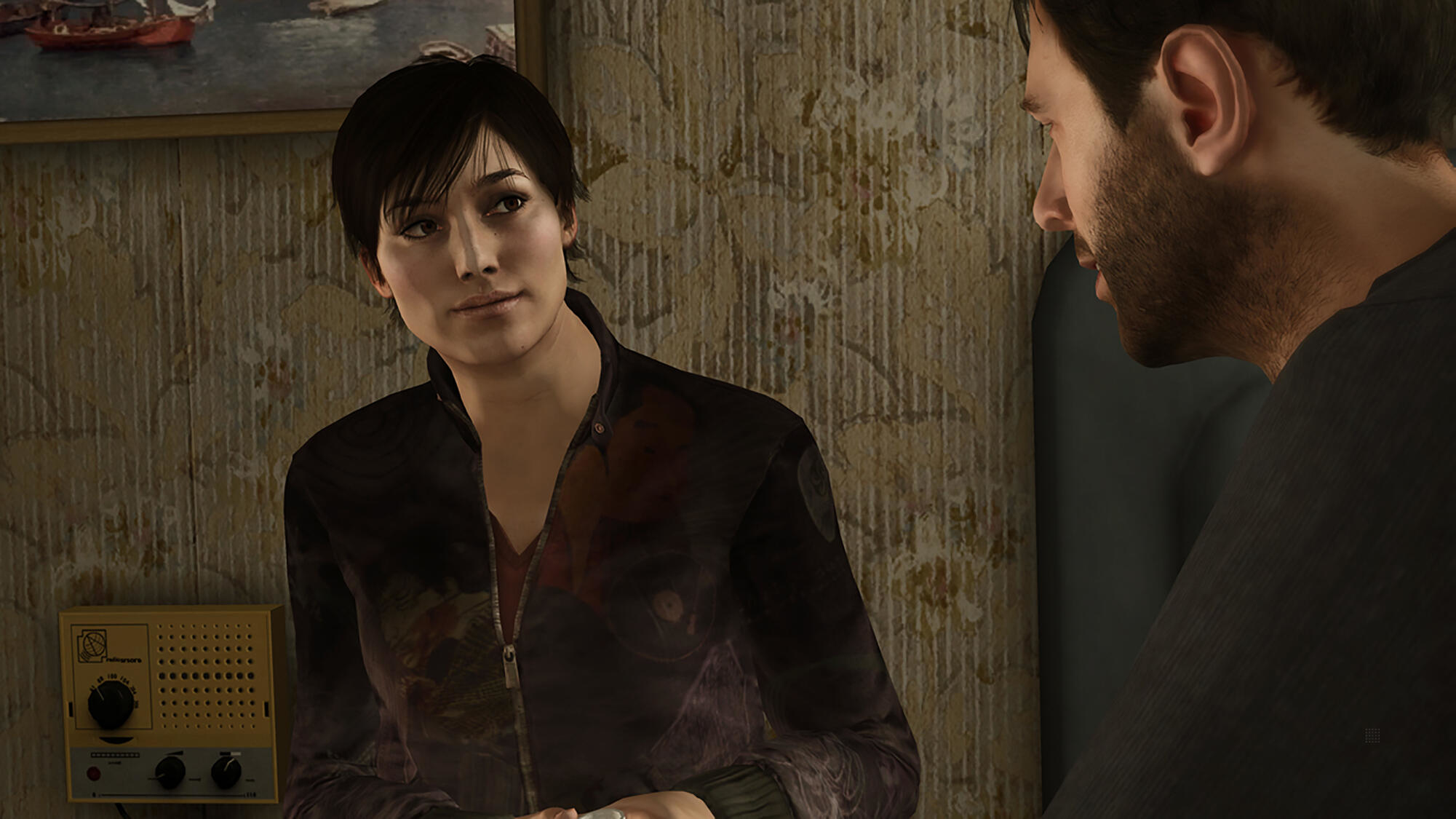 Kobieta rozmawia z mężczyzną. Są w pokoju z kwiatową tapetą.