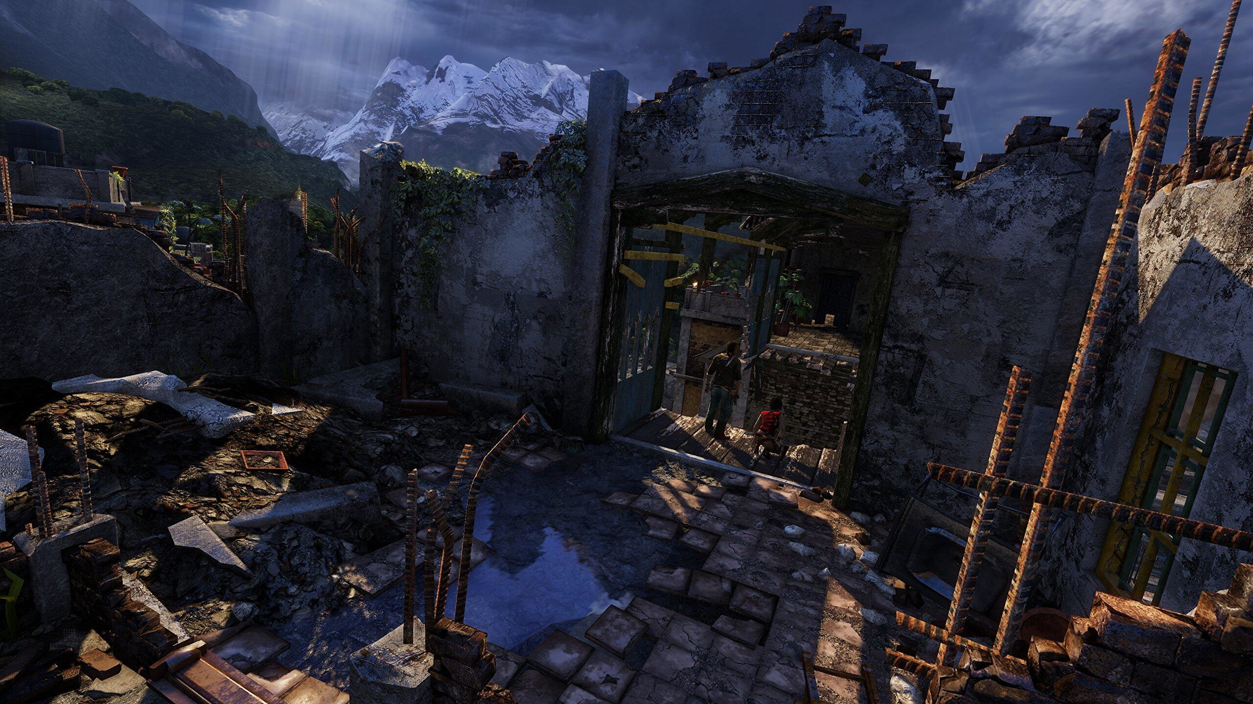 Zrujnowany budynek z widokiem na góry. Dwie osoby wchodzą do środka. Światło słoneczne przechodzi przez otwór.