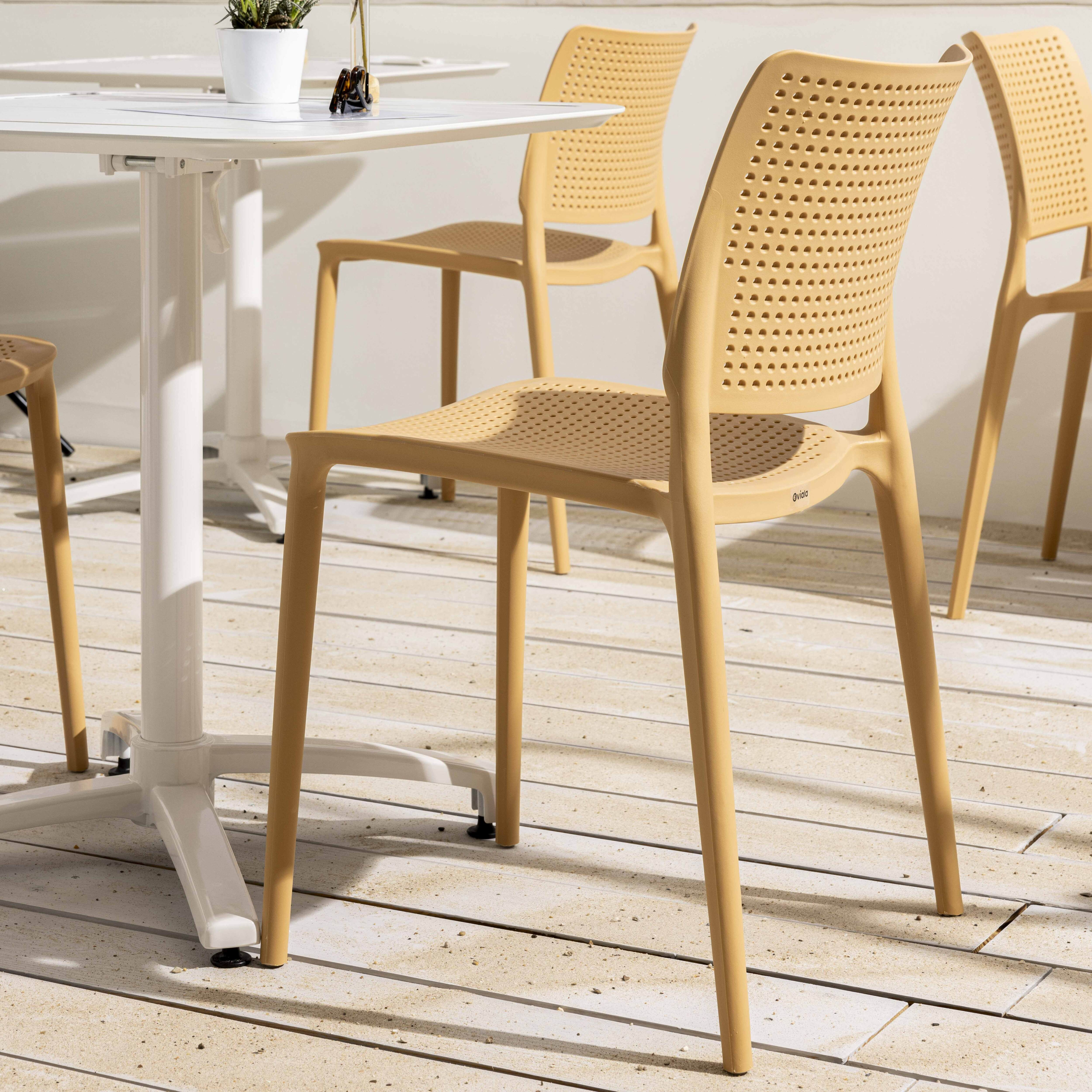 Hellbraune Kunststoffstühle auf einer Terrasse. Weißer Tisch. Hintergrund: Holzterrasse.