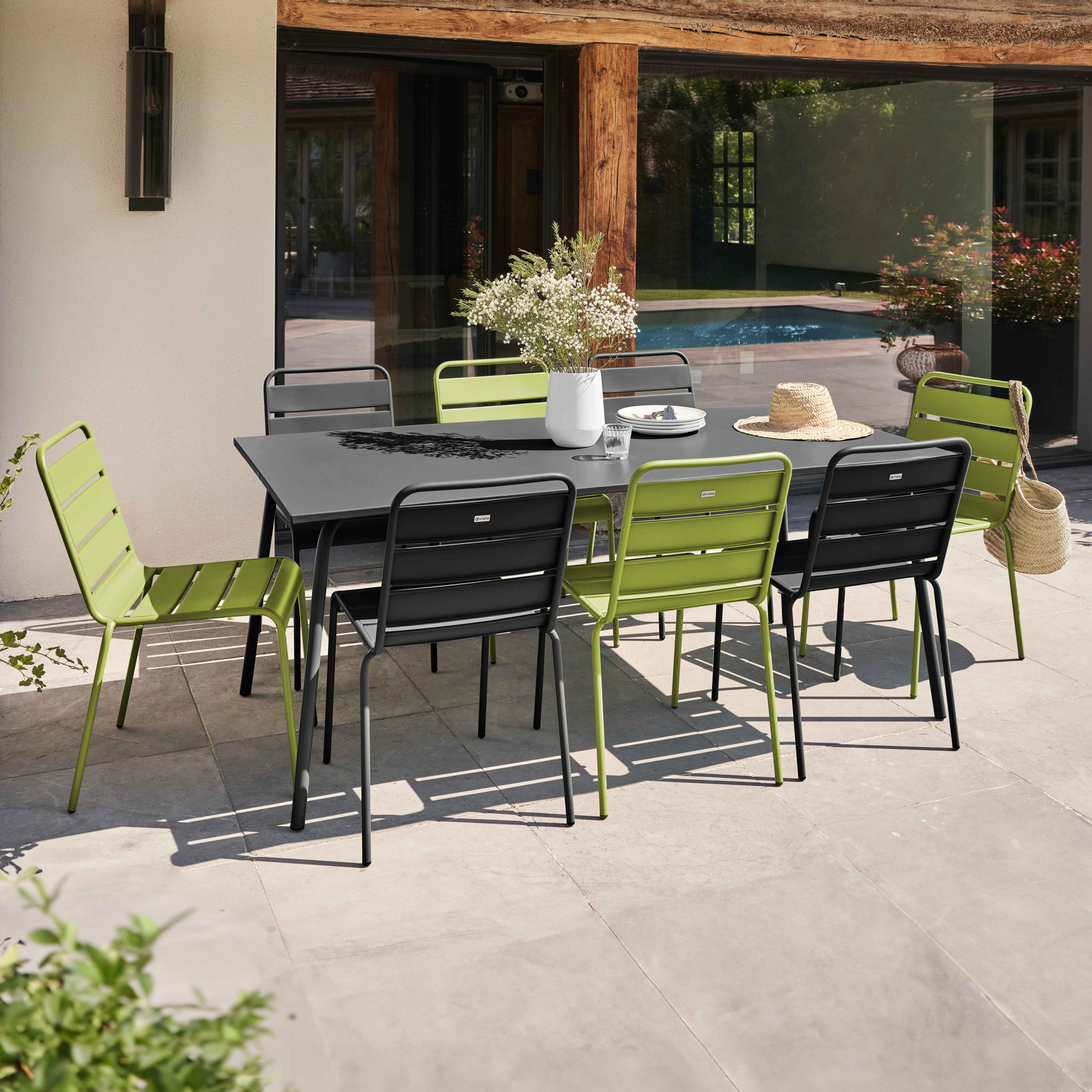 Essgruppe im Freien mit grünen und schwarzen Stühlen. Terrasse.