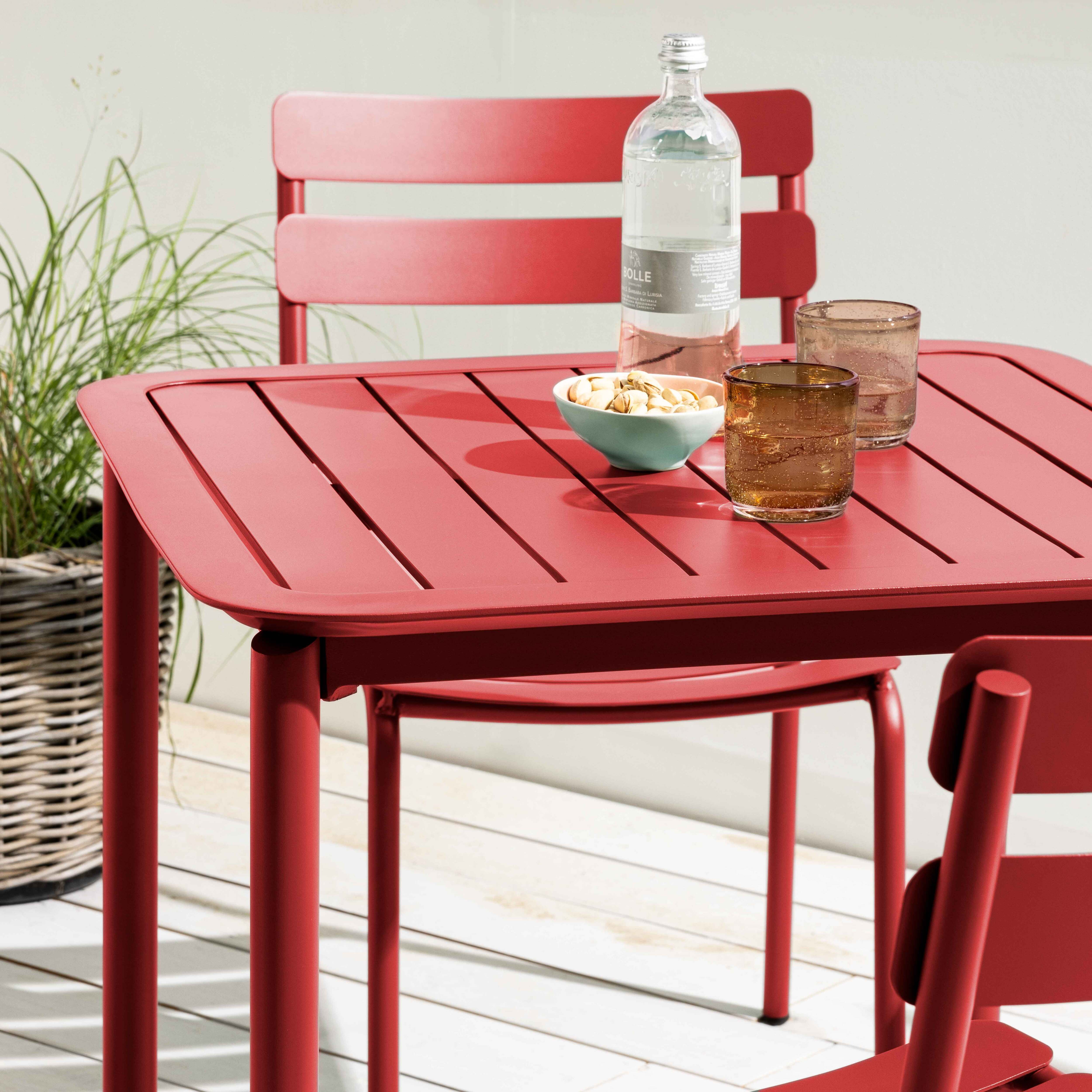 Rotes Ess-Set im Freien: Tisch, Stühle, Wasserflasche, Snacks.