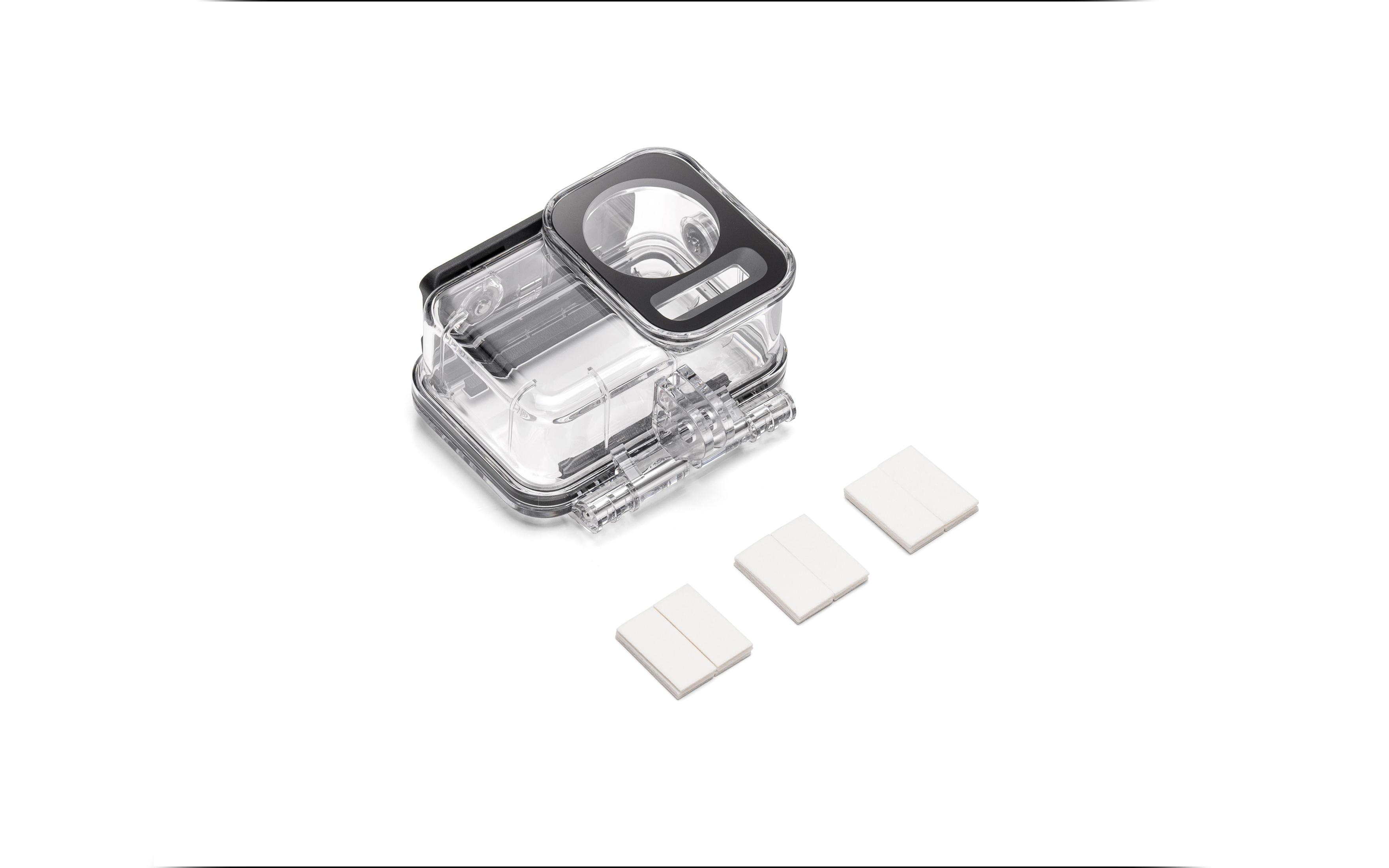 Przezroczysta, wodoodporna obudowa kamery z trzema białymi prostokątnymi podkładkami na białej powierzchni.