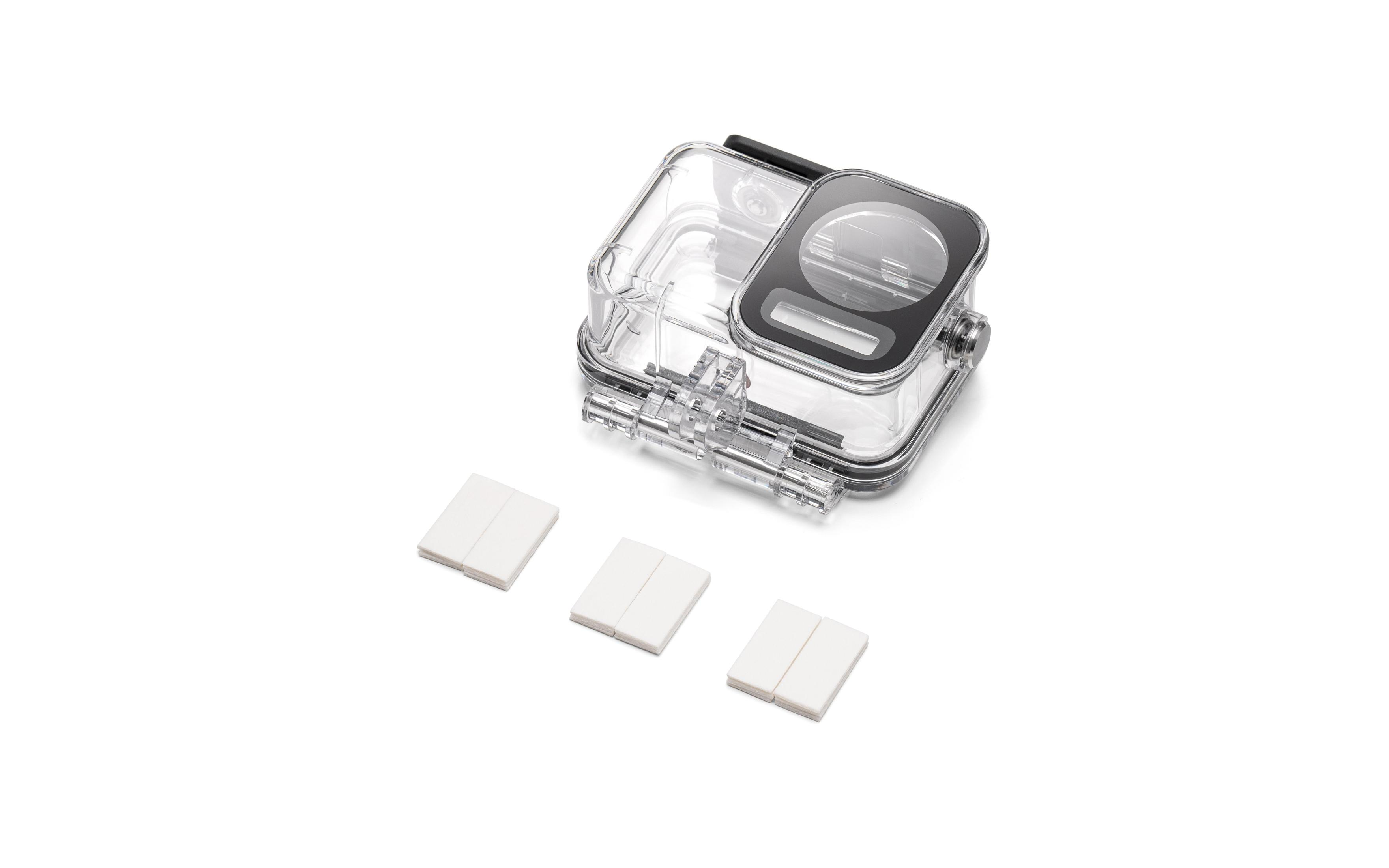 Przezroczysta, wodoodporna obudowa kamery z trzema białymi prostokątnymi podkładkami na białej powierzchni.