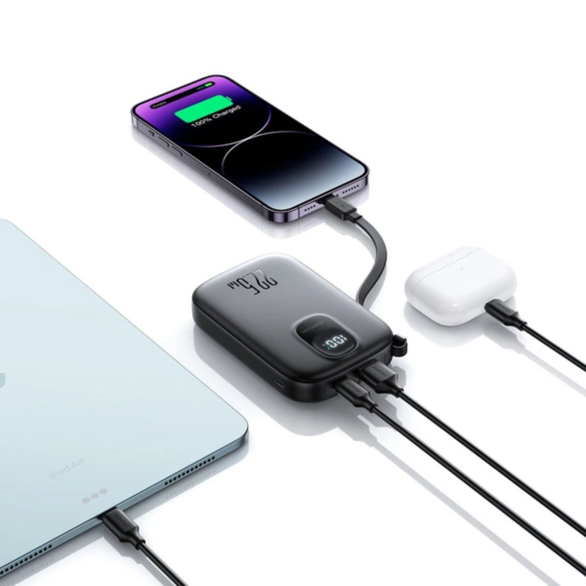 Czarny power bank ładujący telefon, iPada i słuchawki AirPods. Wyświetla procenty ładowania na urządzeniach.