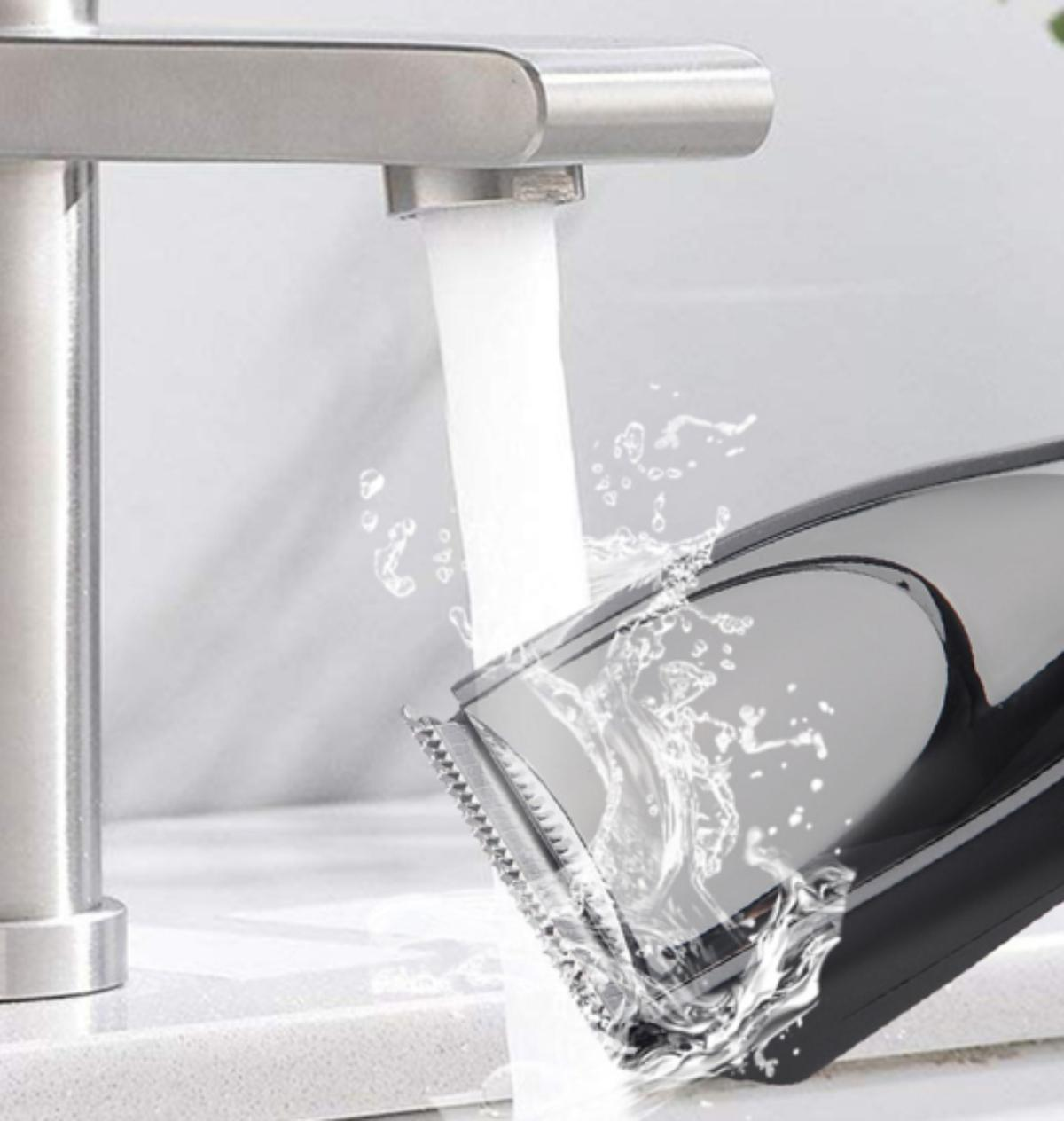 Haarschneider unter fließendem Wasser. Wasser spritzt auf die Klingen.