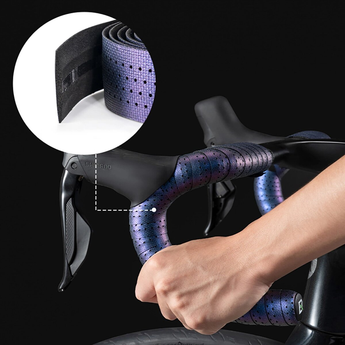 Hände wickeln einen Fahrradlenker mit blau-lila gemustertem Band. Der Lenker ist schwarz.